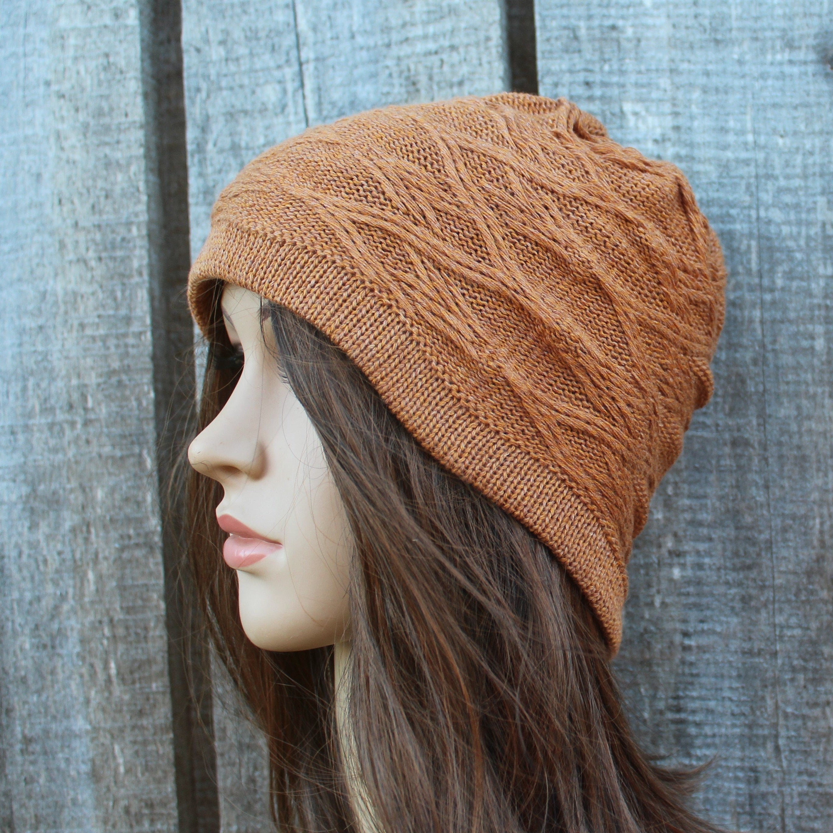 Brown knitted beanie on a mannequin head against a wooden background