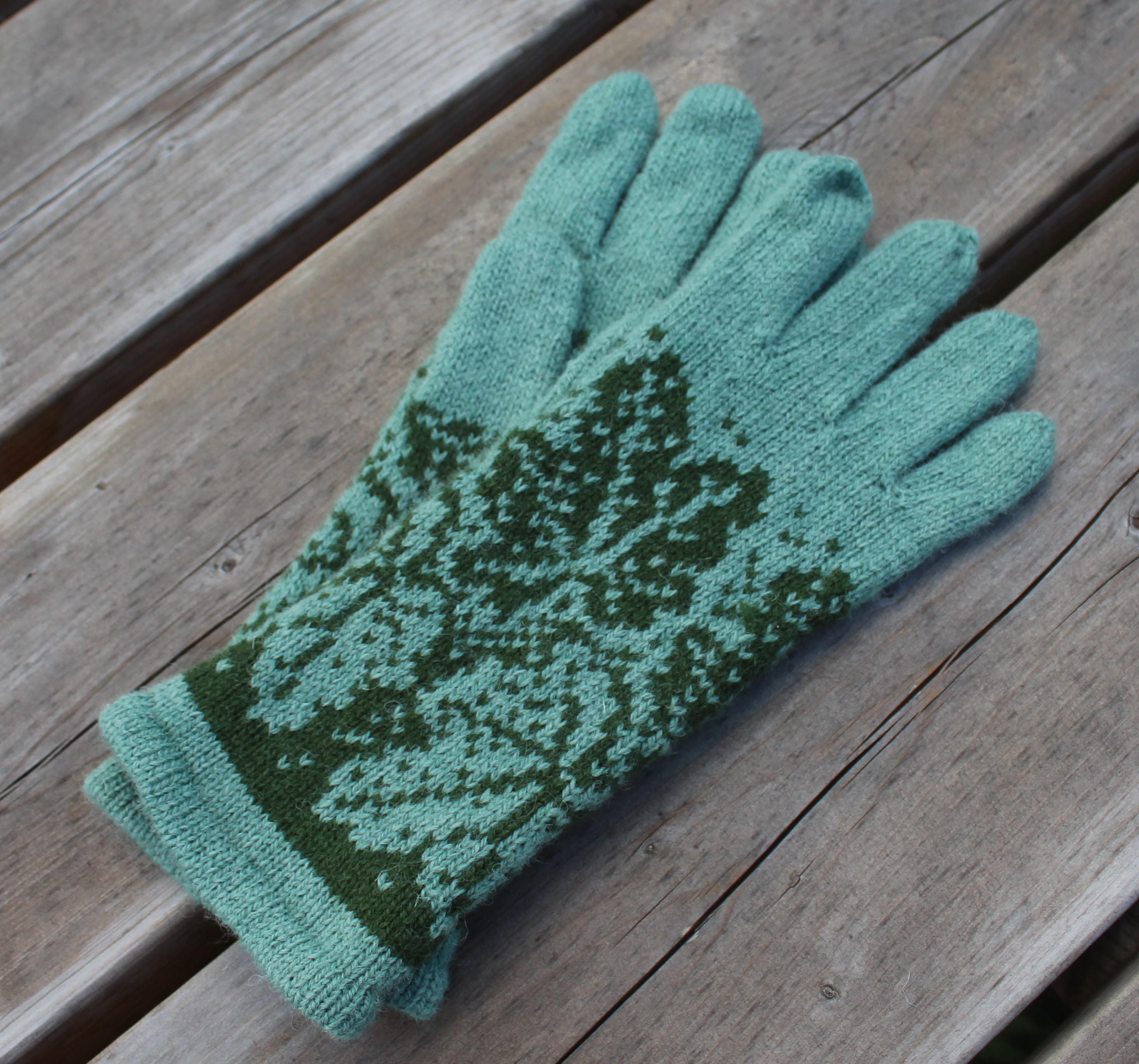 Green knitted gloves with a pattern on a wooden surface