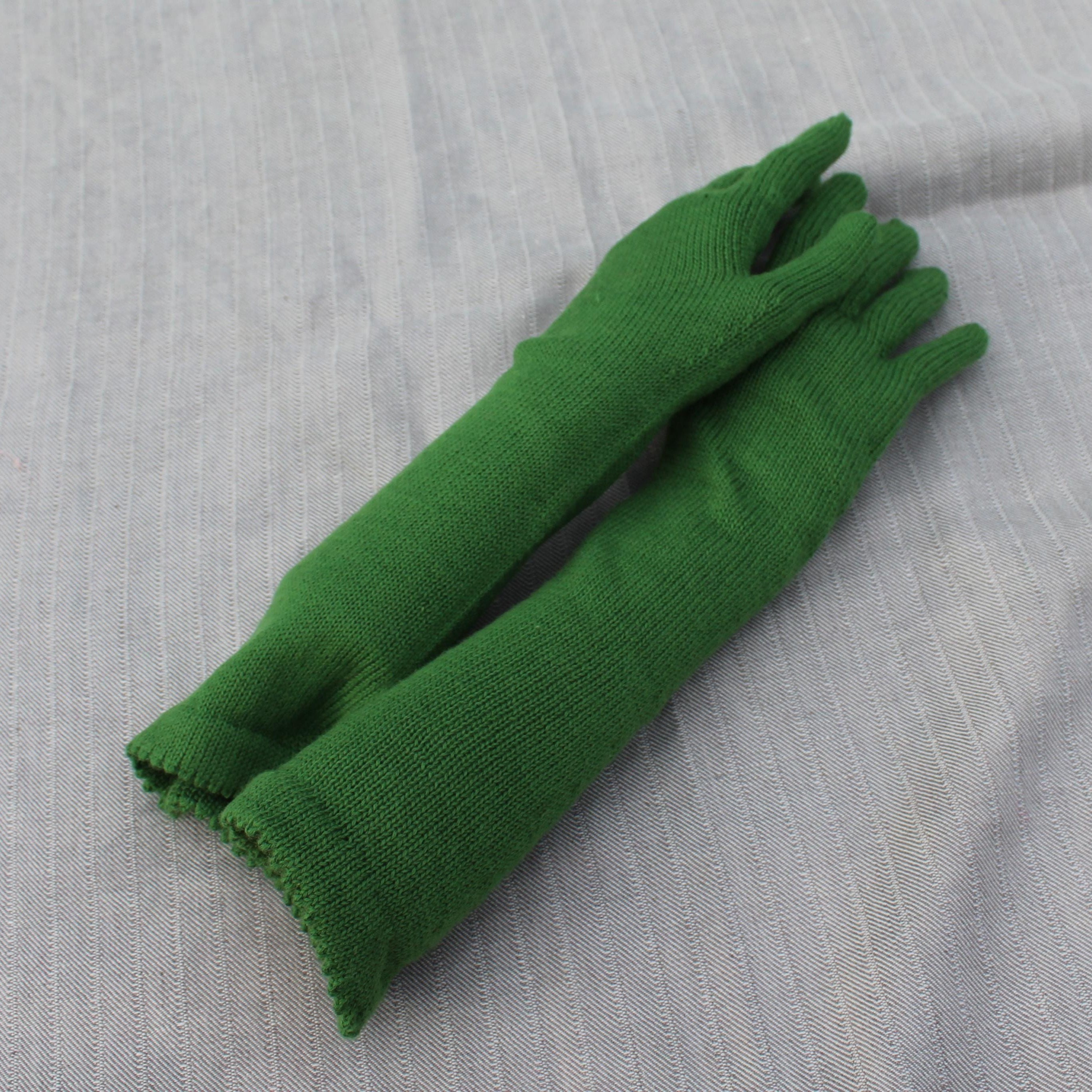 Pair of green gloves on a gray textured background