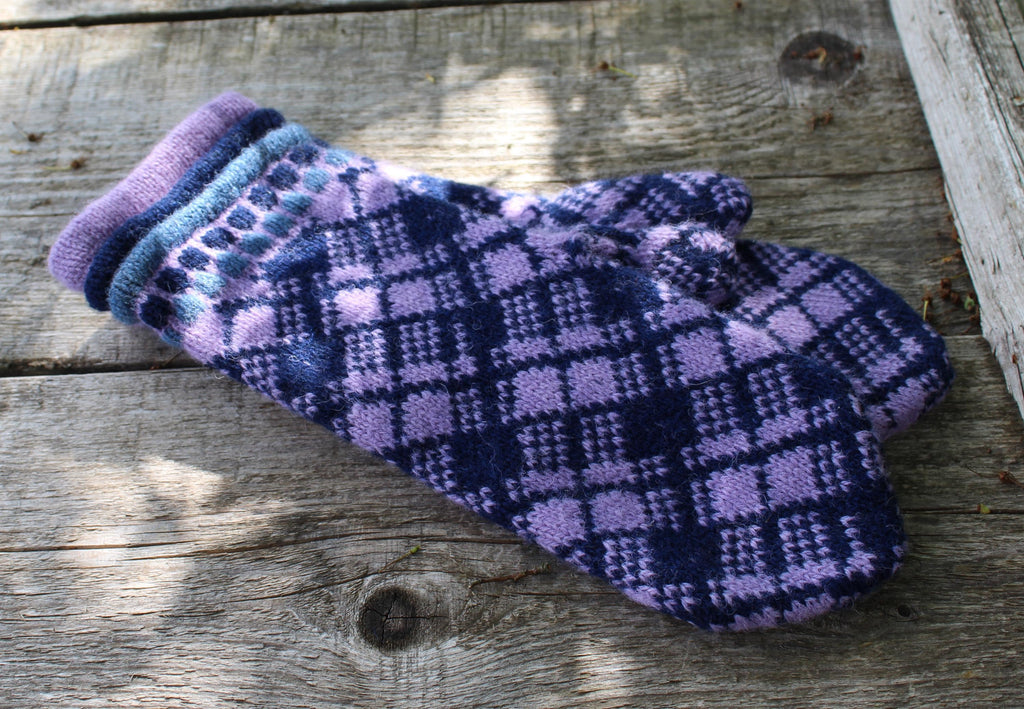 Pair of purple and blue checkered mittens on a wooden surface