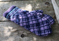 Pair of purple and blue checkered mittens on a wooden surface