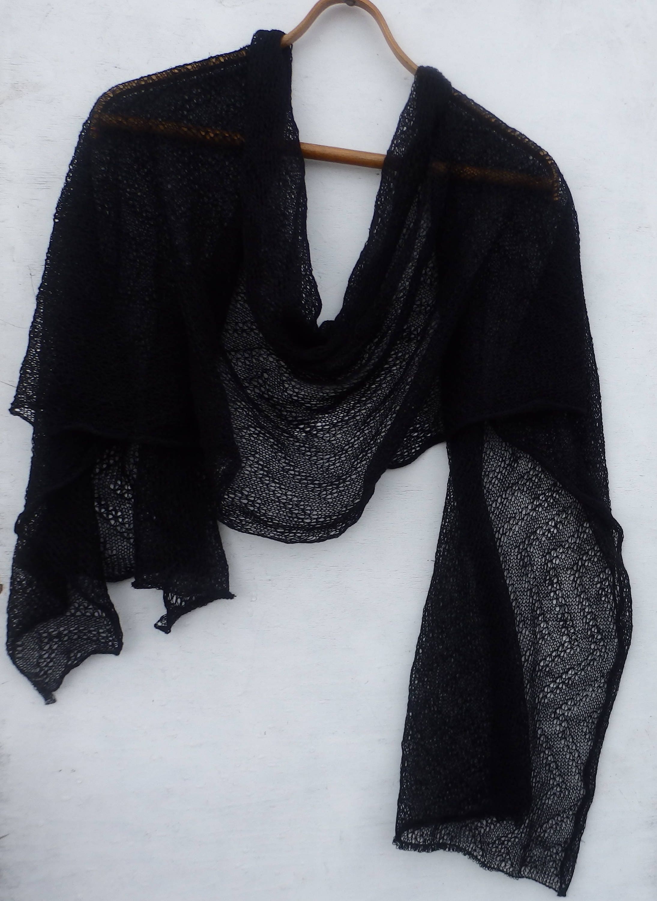 Black shawl draped over a wooden hanger on a white background