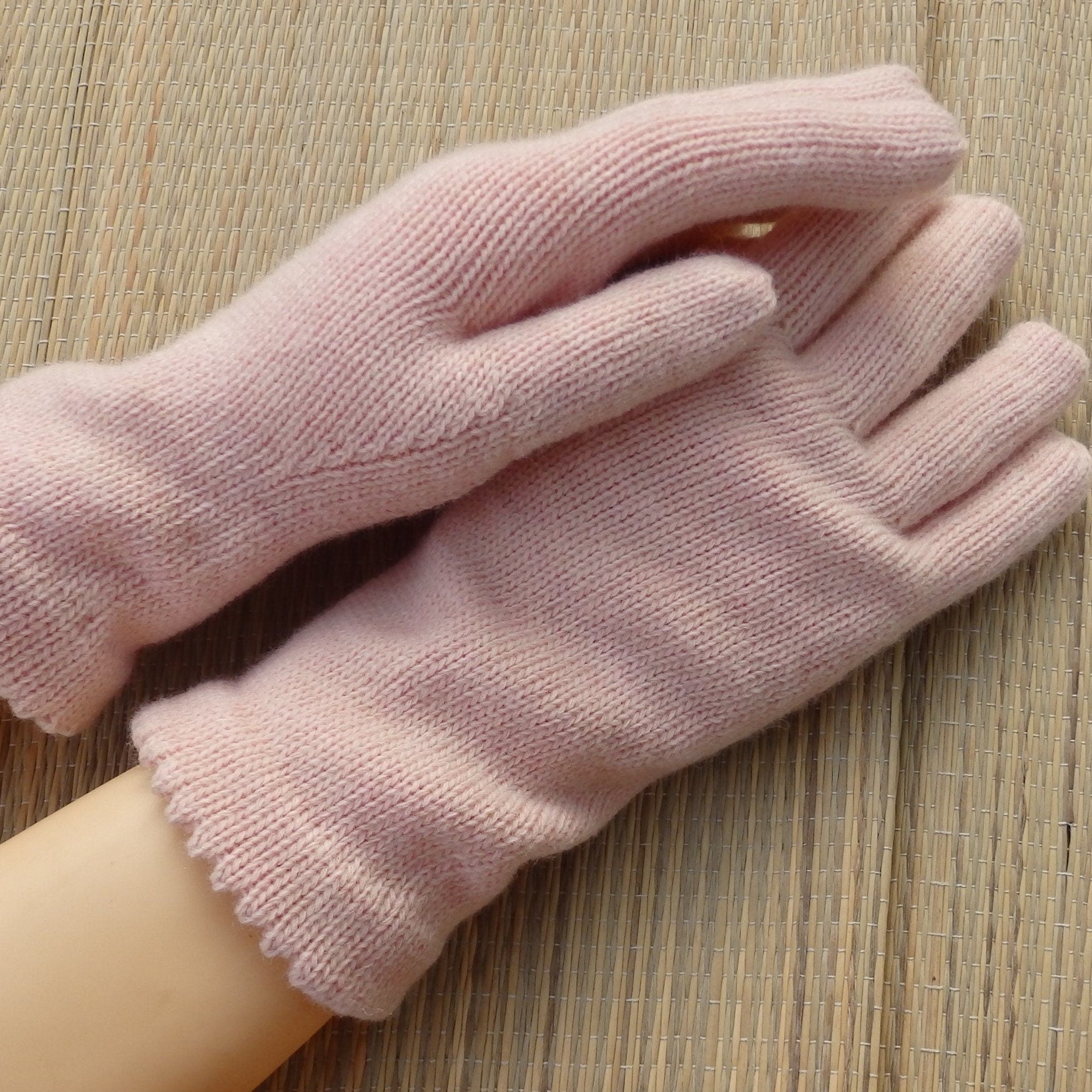 Pair of pink gloves on a wooden surface