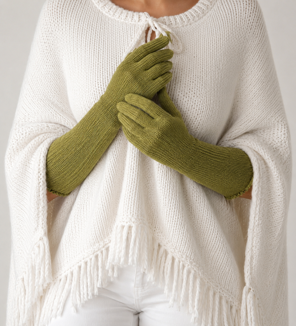 Person wearing a white sweater and green gloves against a neutral background