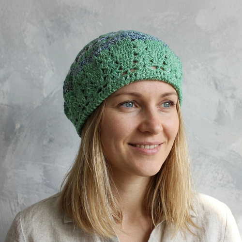 Woman wearing a green crocheted beanie against a gray background