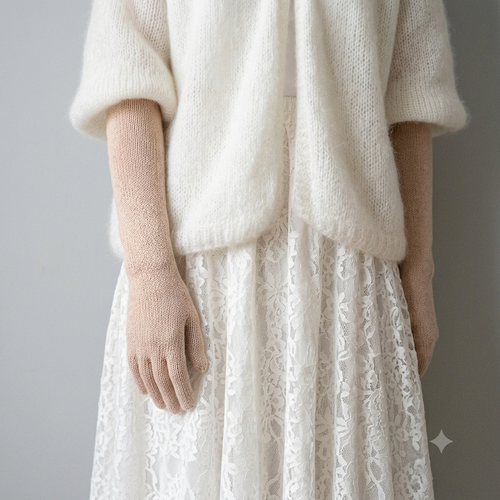 Person wearing a white knit sweater and beige gloves with a white lace skirt on a gray background