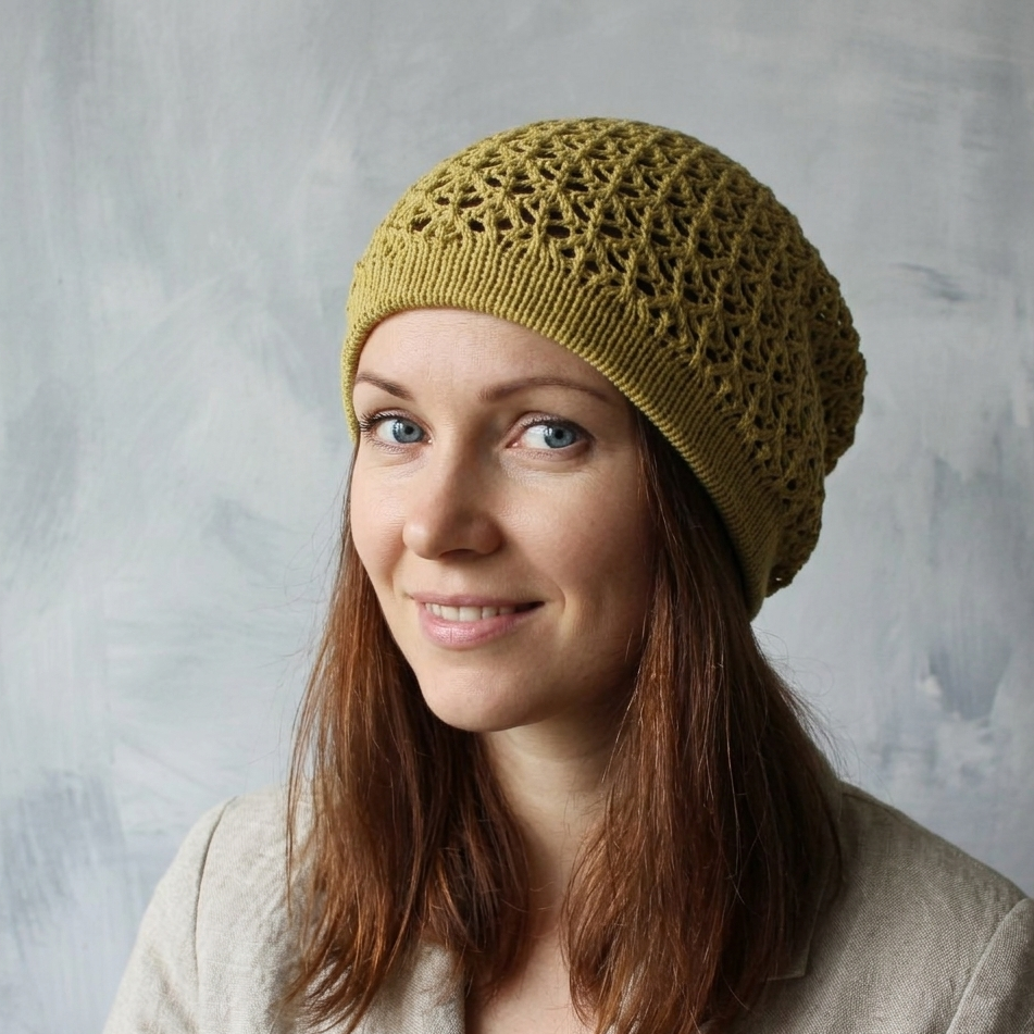 Woman wearing a green knitted beanie against a gray background