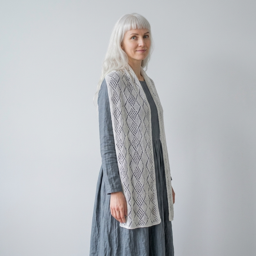 Woman wearing a long, light-colored cardigan over a gray dress against a plain background