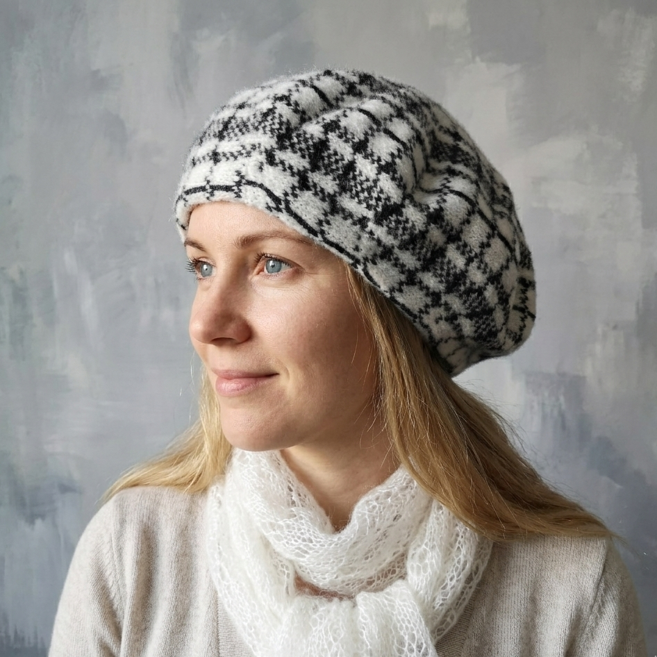 Woman wearing a patterned knit hat and white scarf against a gray background