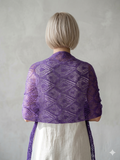 Person wearing a purple knitted shawl against a plain background