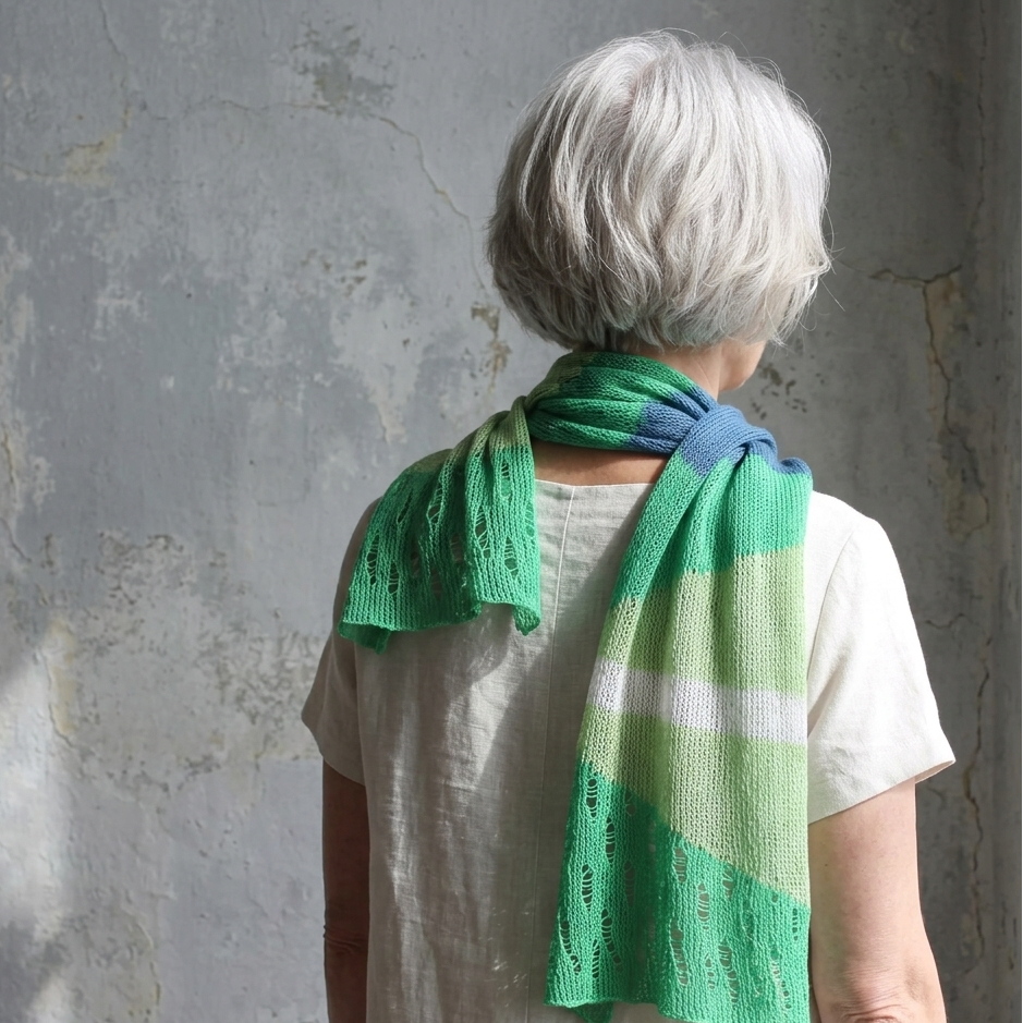 Person wearing a green knitted shawl against a textured wall