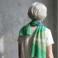 Person wearing a green knitted shawl against a textured wall
