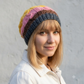 Woman wearing a colorful striped beanie against a plain background