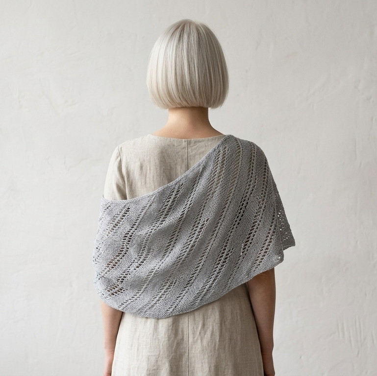 Person wearing a gray knitted shawl over a plain background