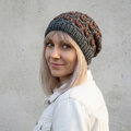Woman wearing a knitted beanie with a textured pattern against a plain background