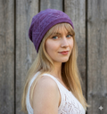 Woman wearing a purple knitted hat against a wooden background