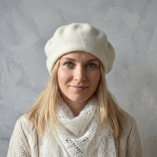 Woman wearing a white beret and scarf against a gray background
