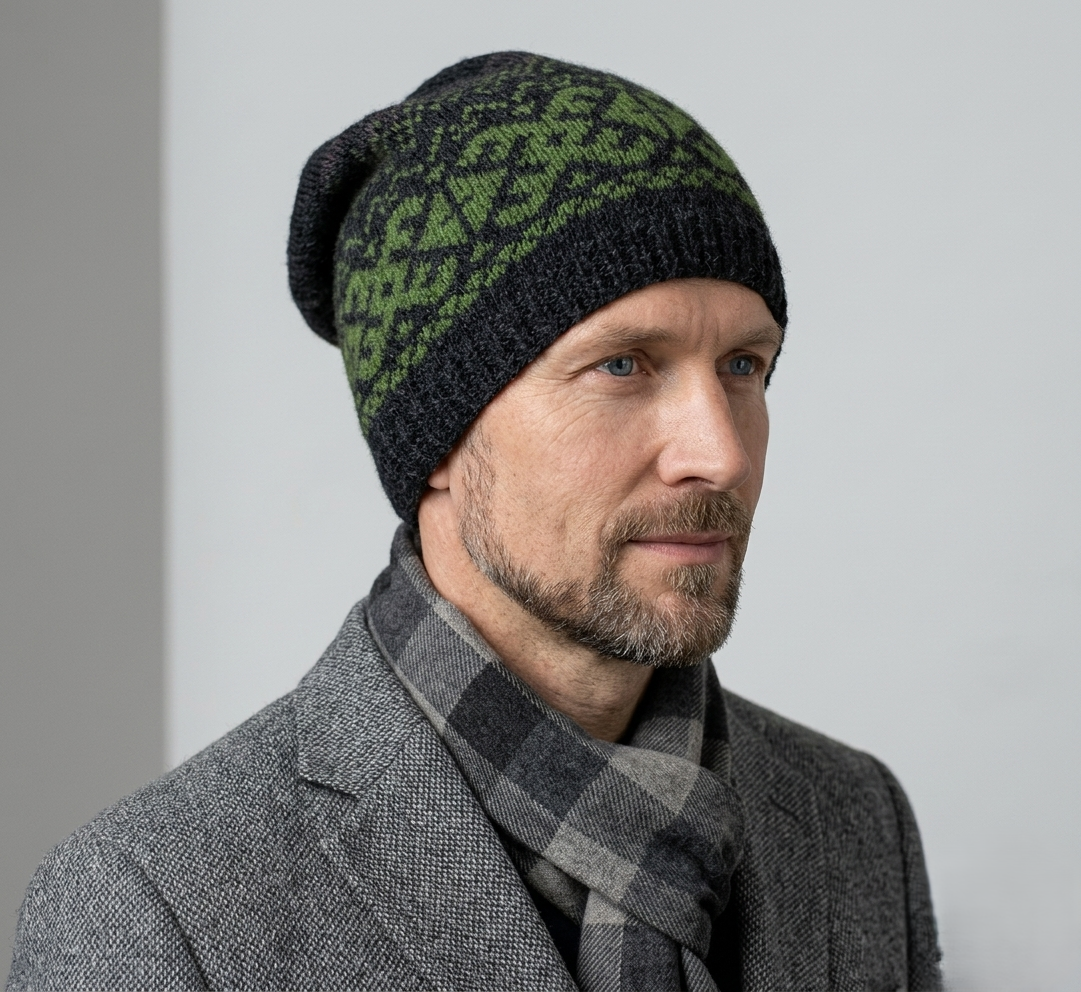 Man wearing a black and green patterned beanie and gray scarf against a light gray background