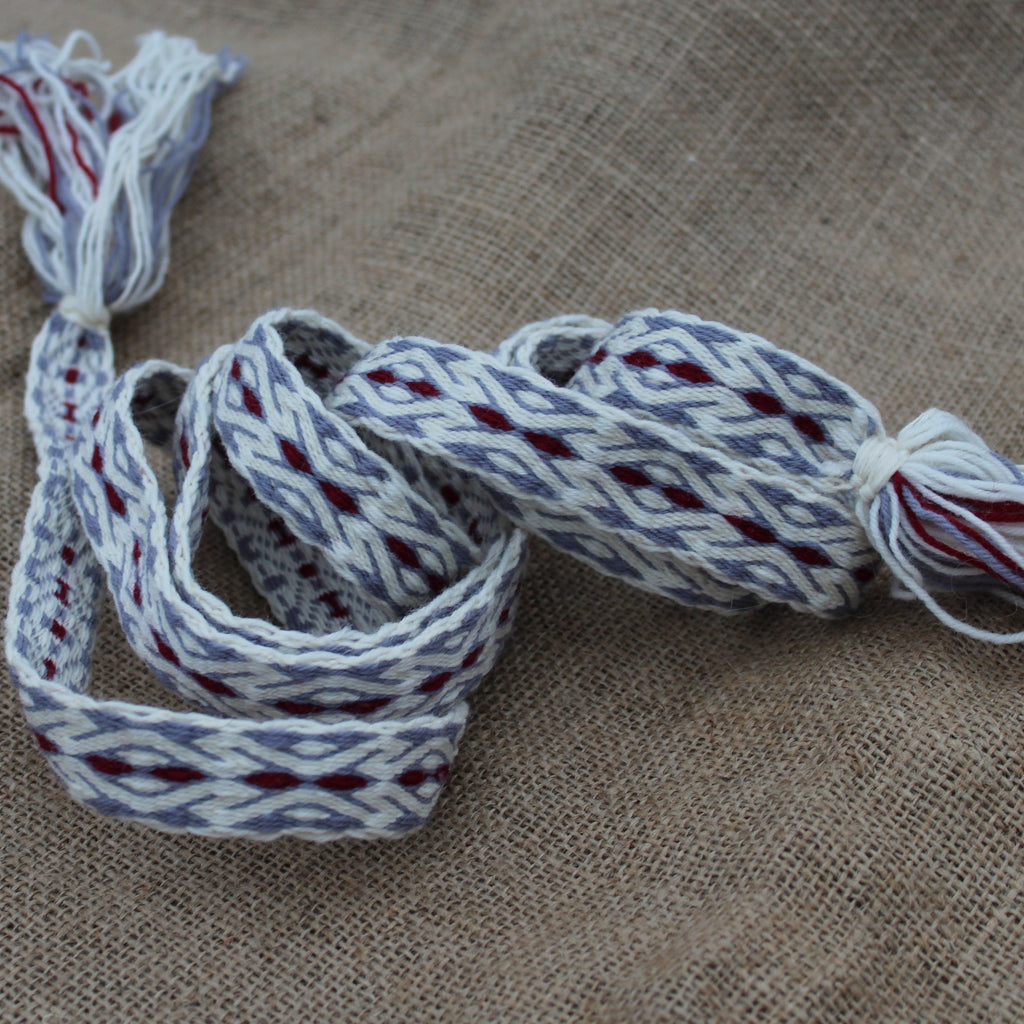 Woven belt with red and gray patterns on a textured brown surface