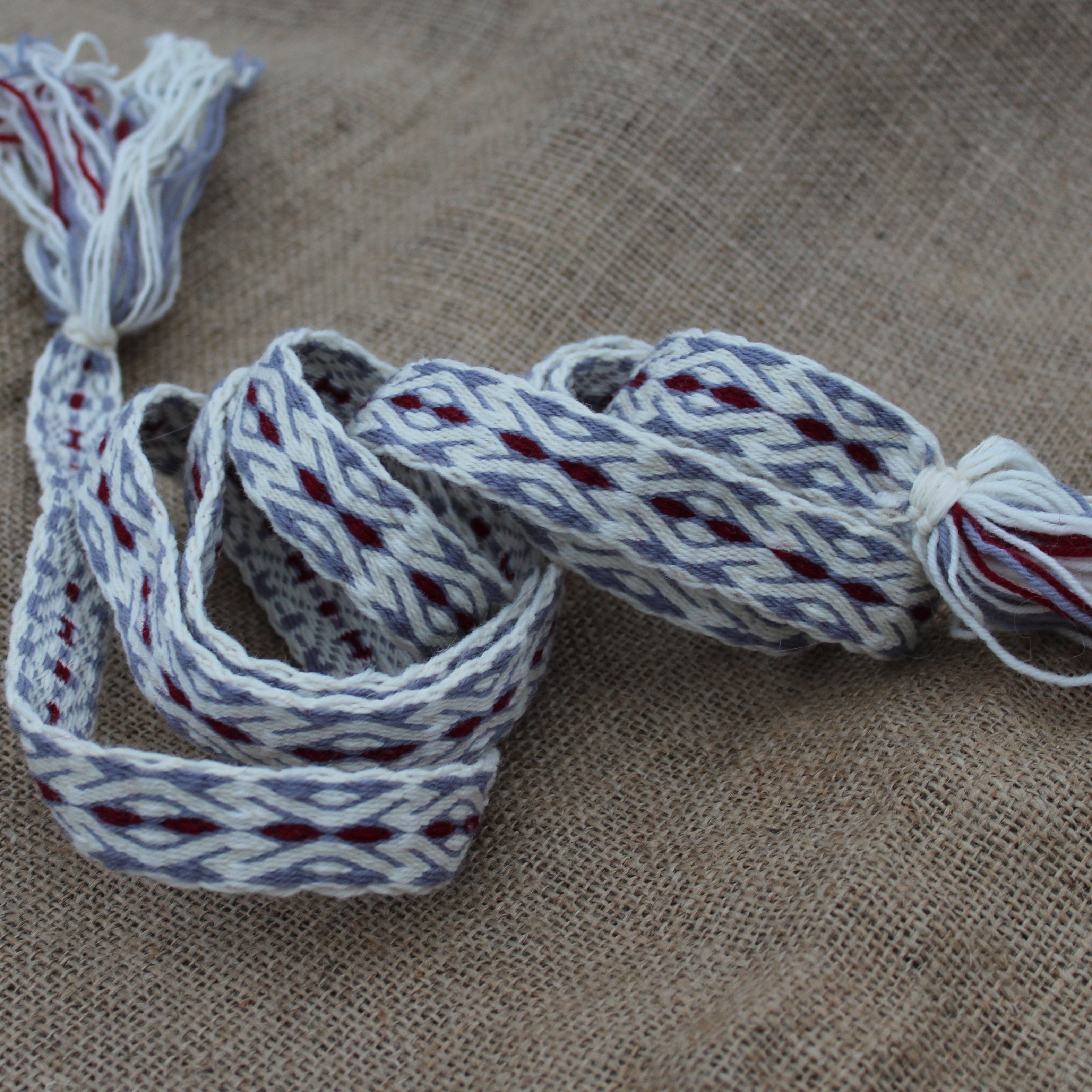 Woven belt with red and gray patterns on a textured brown surface