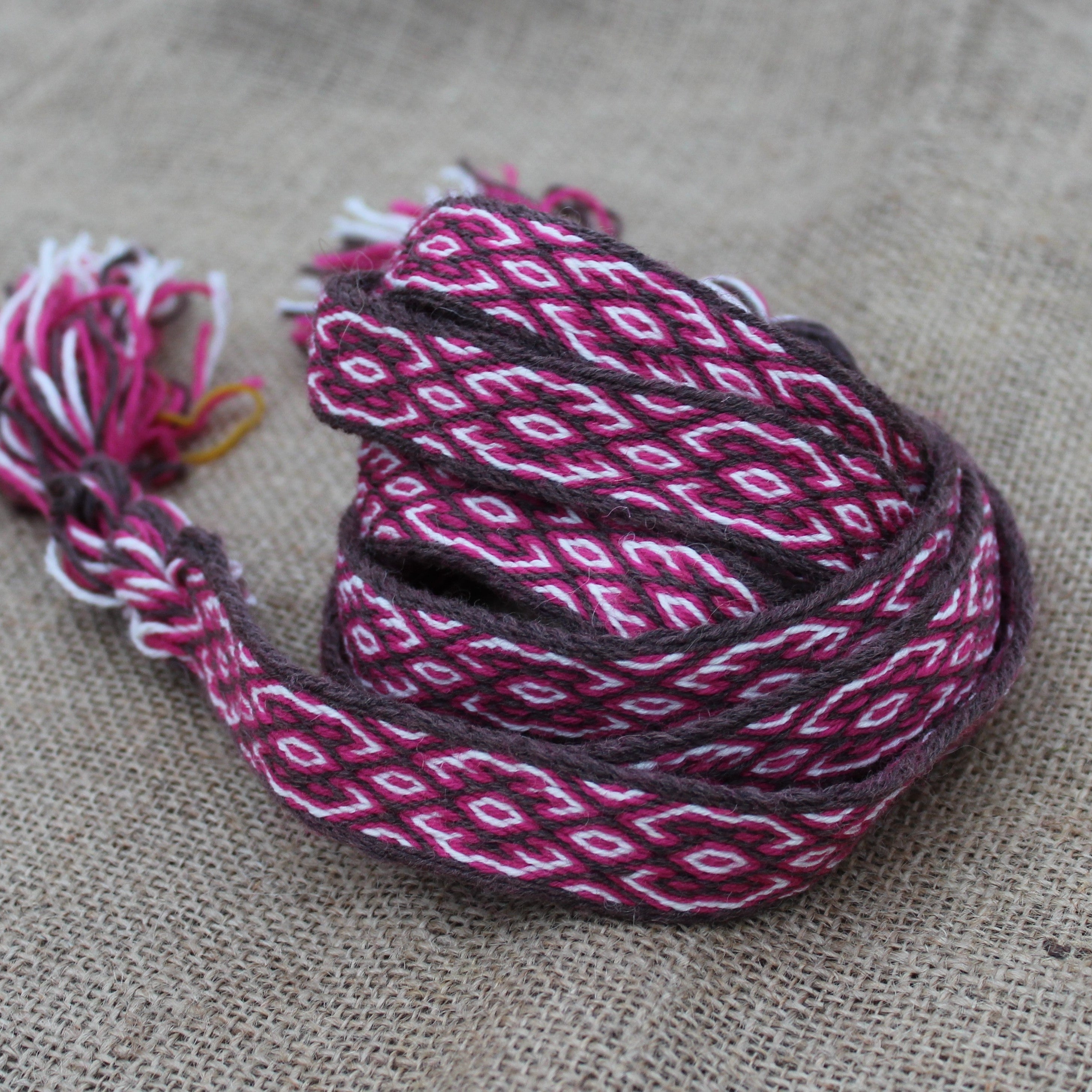 Woven belt with white and red  pattern on a textured fabric background