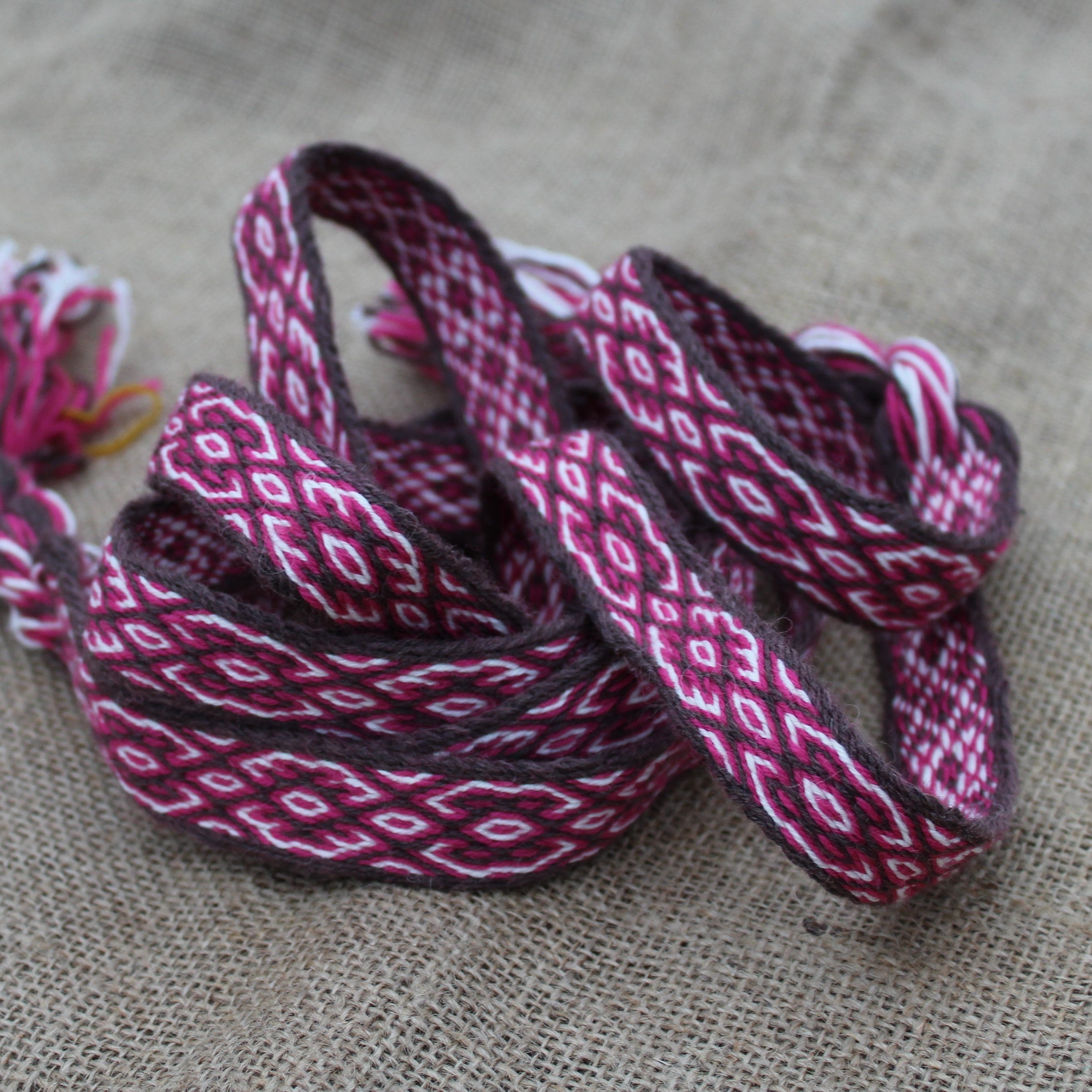Woven belt with red and white patterns on a textured fabric background