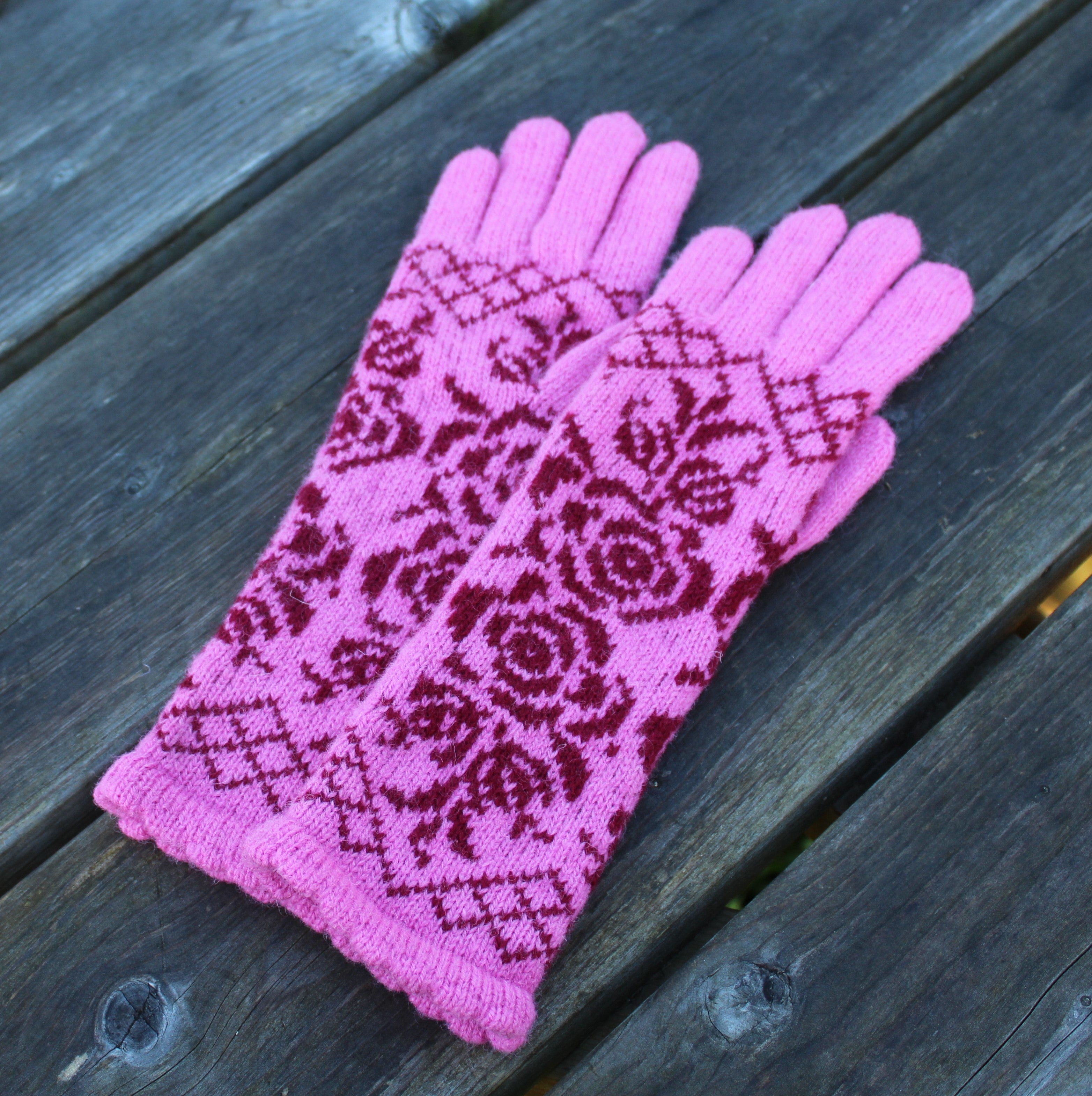 Pink gloves with a red pattern on a wooden surface