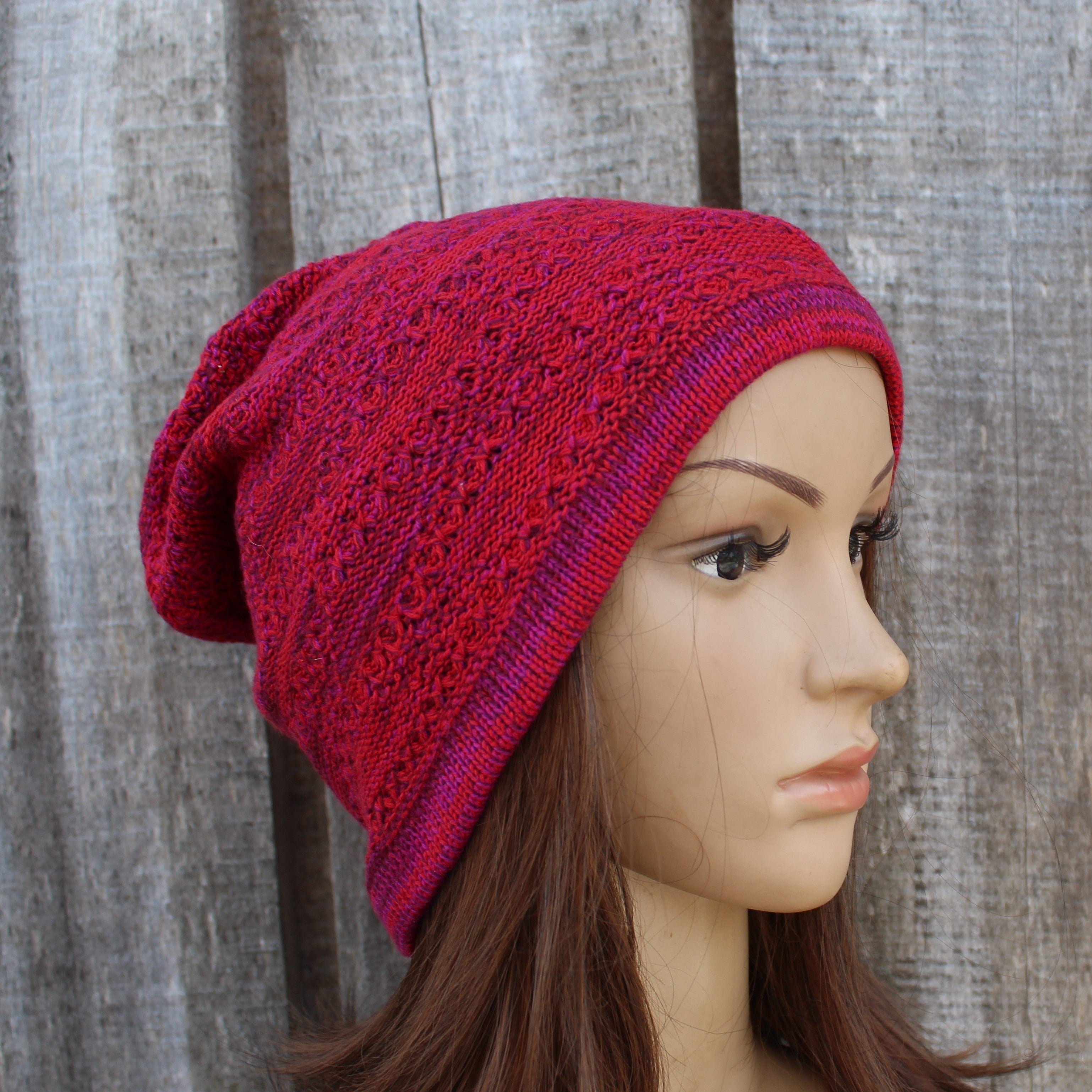 Red knitted beanie on a mannequin head against a wooden background