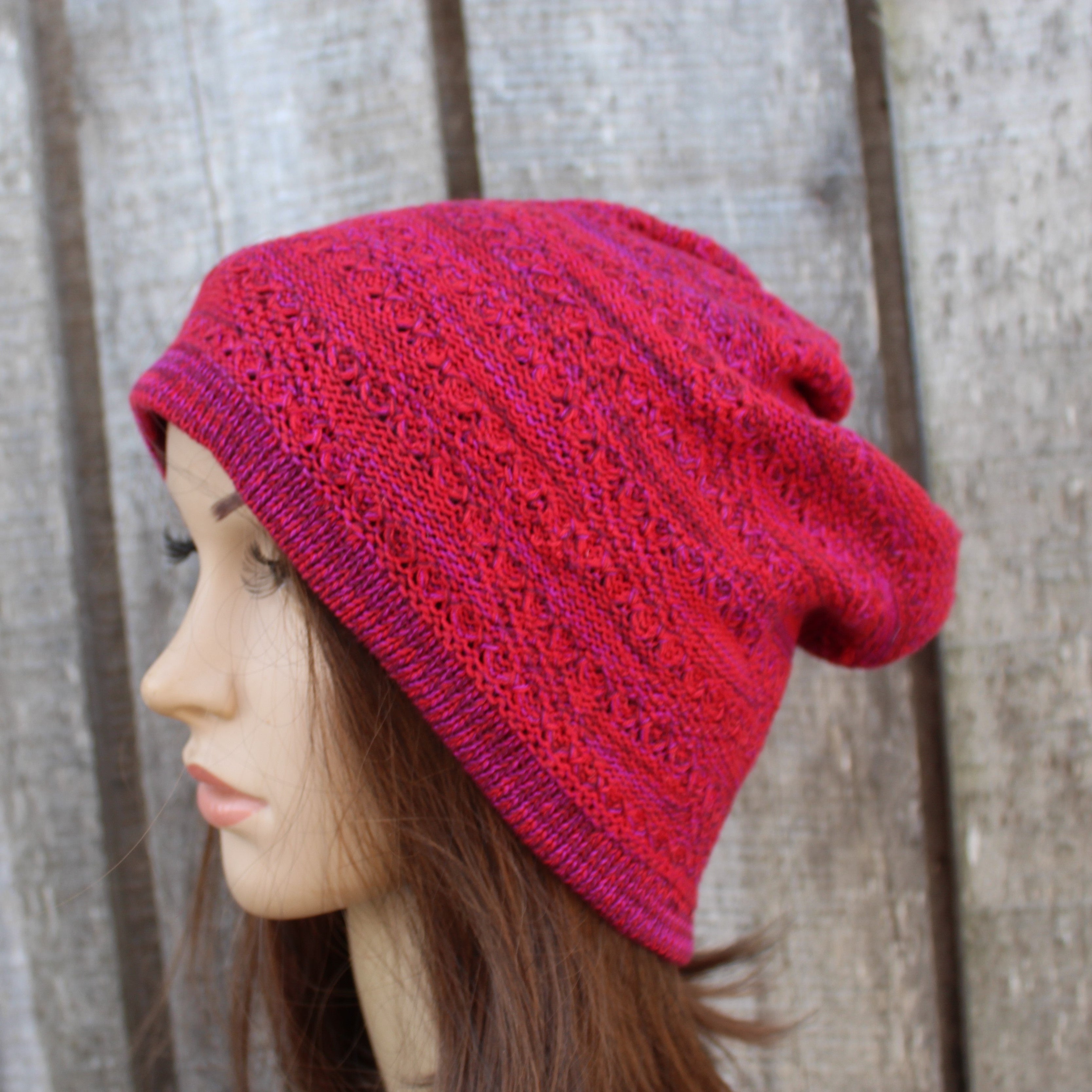 Red knitted hat on a mannequin head against a wooden background