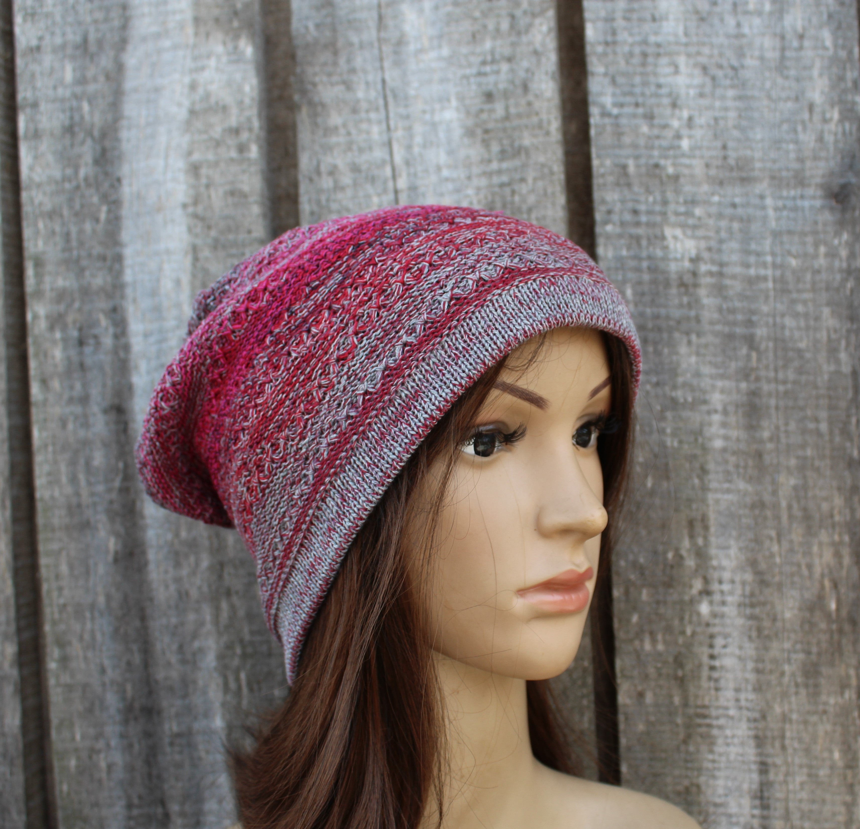 Mannequin head wearing a pink and gray patterned knit beanie against a wooden background