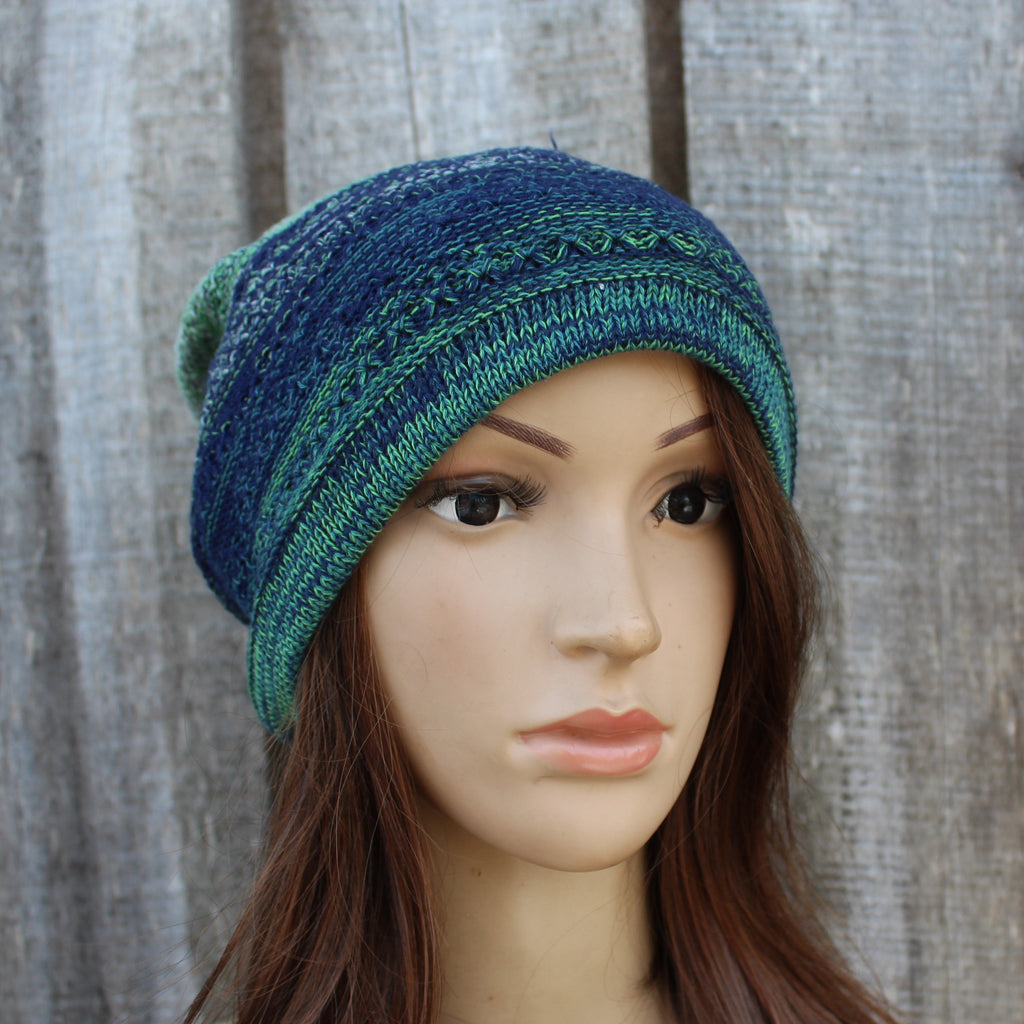 Blue and green knitted beanie on a mannequin head against a wooden background