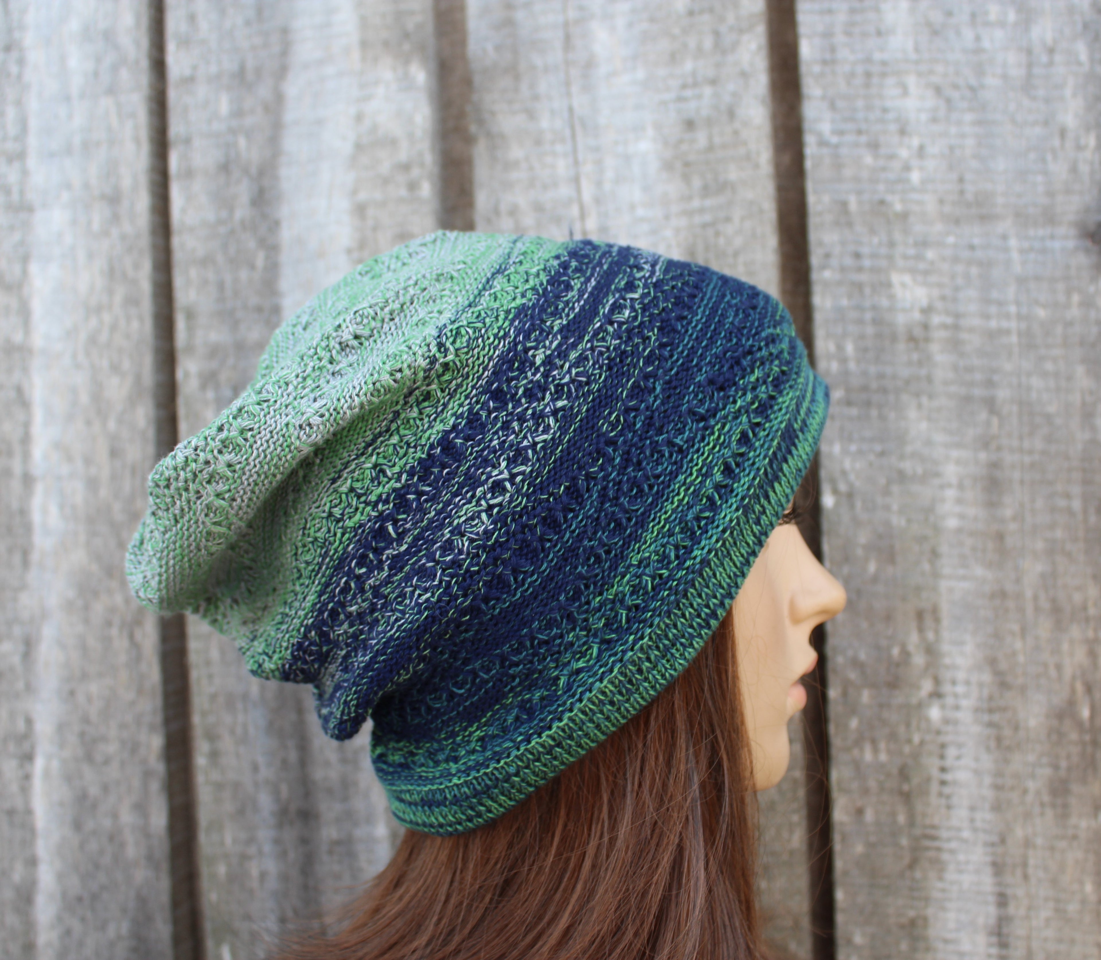 Knitted hat with green and blue gradient on a wooden background