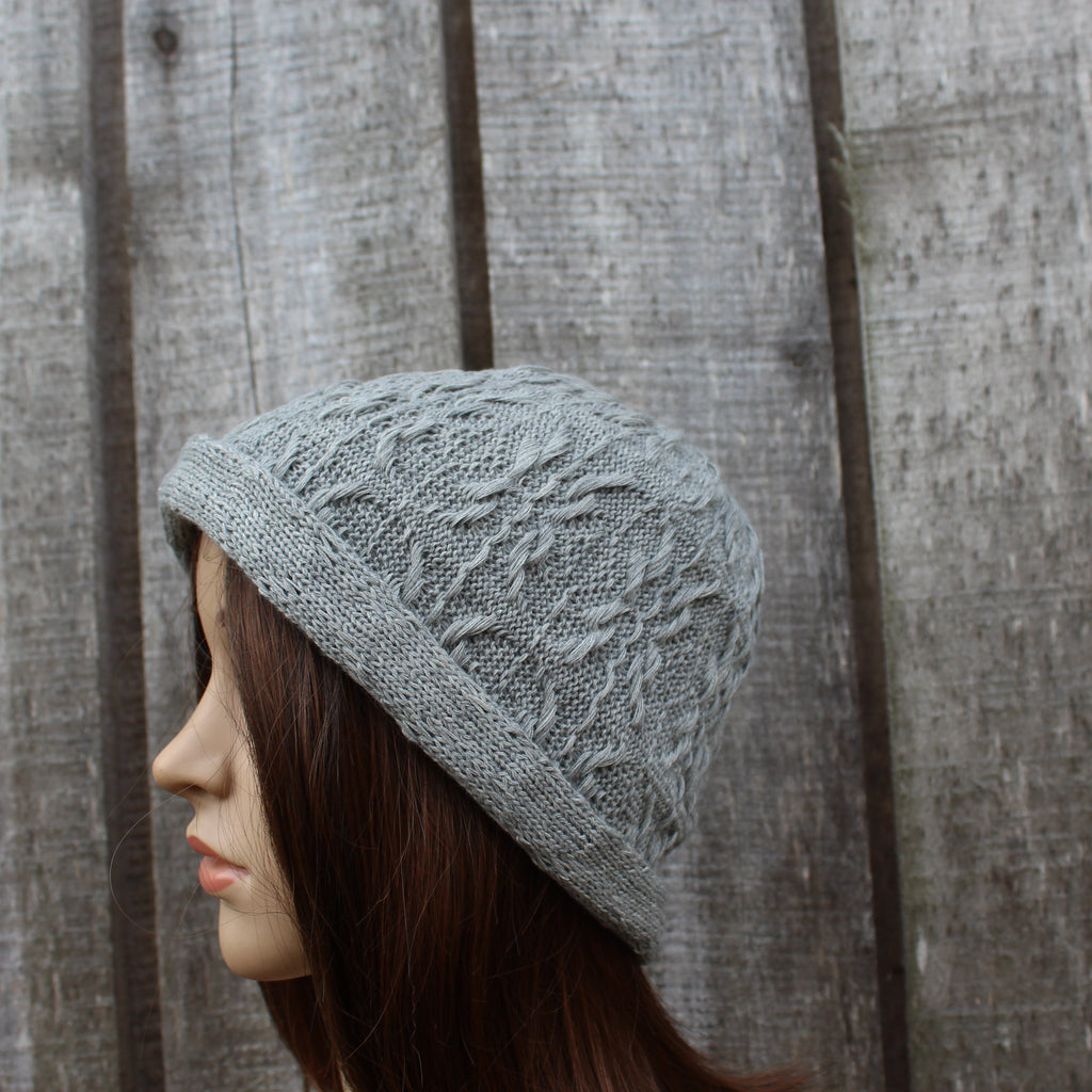 Knitted gray hat on a mannequin head against a wooden background