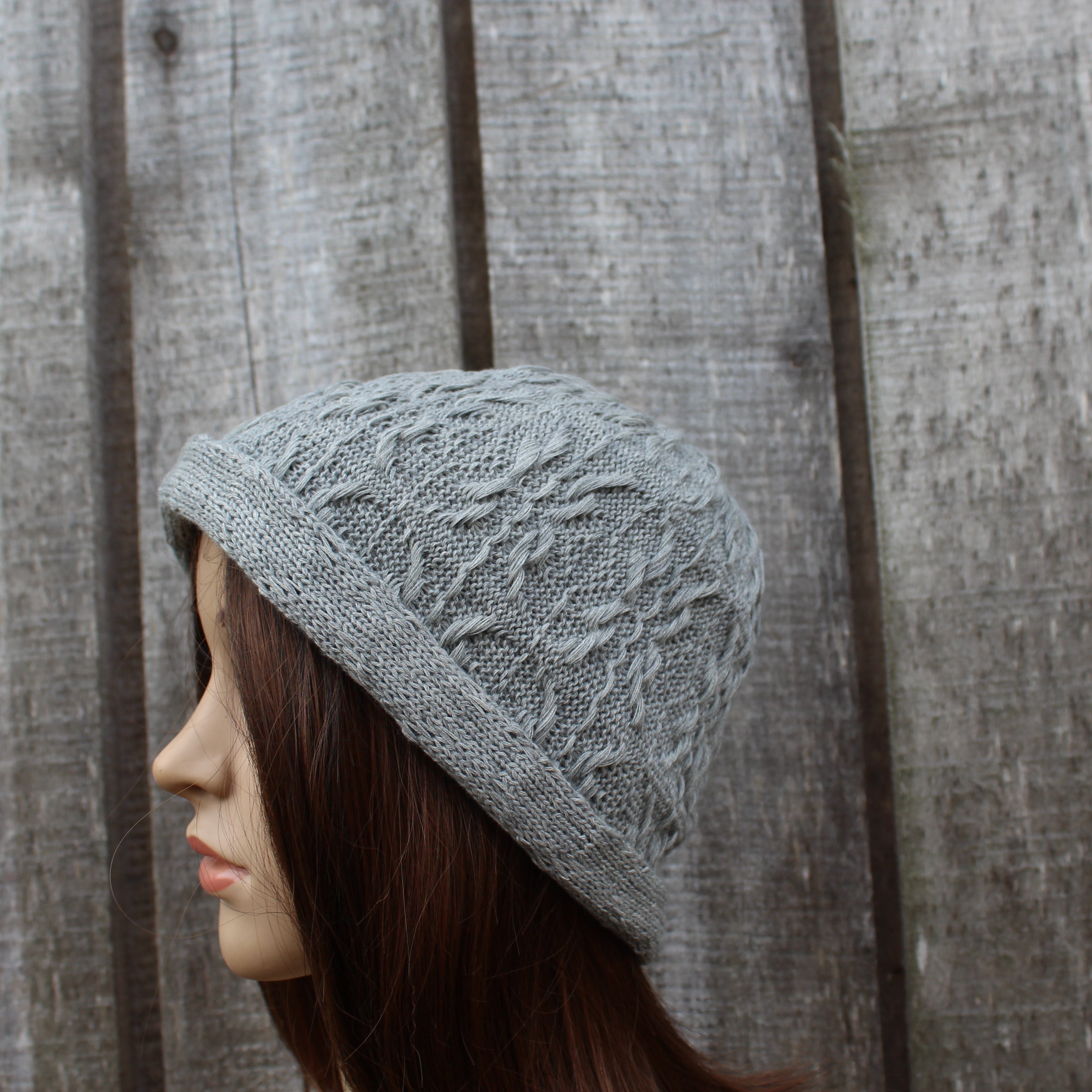 Knitted gray hat on a mannequin head against a wooden background