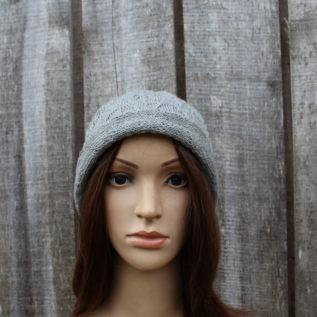 Mannequin head wearing a gray knit beanie against a wooden panel background