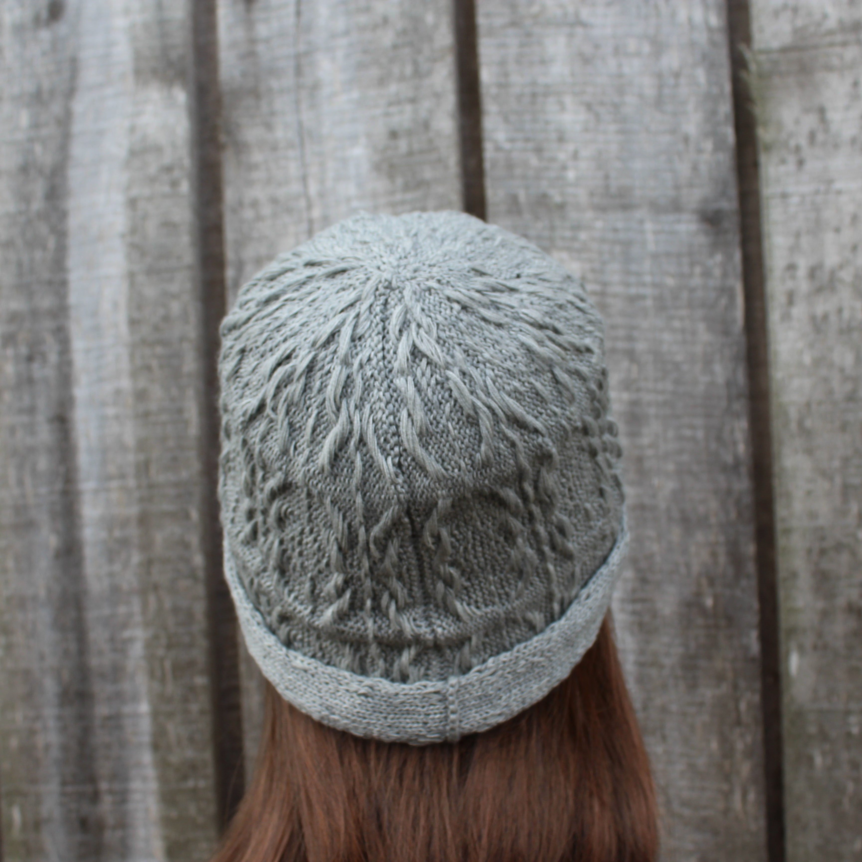 Person wearing a knitted hat against a wooden fence background