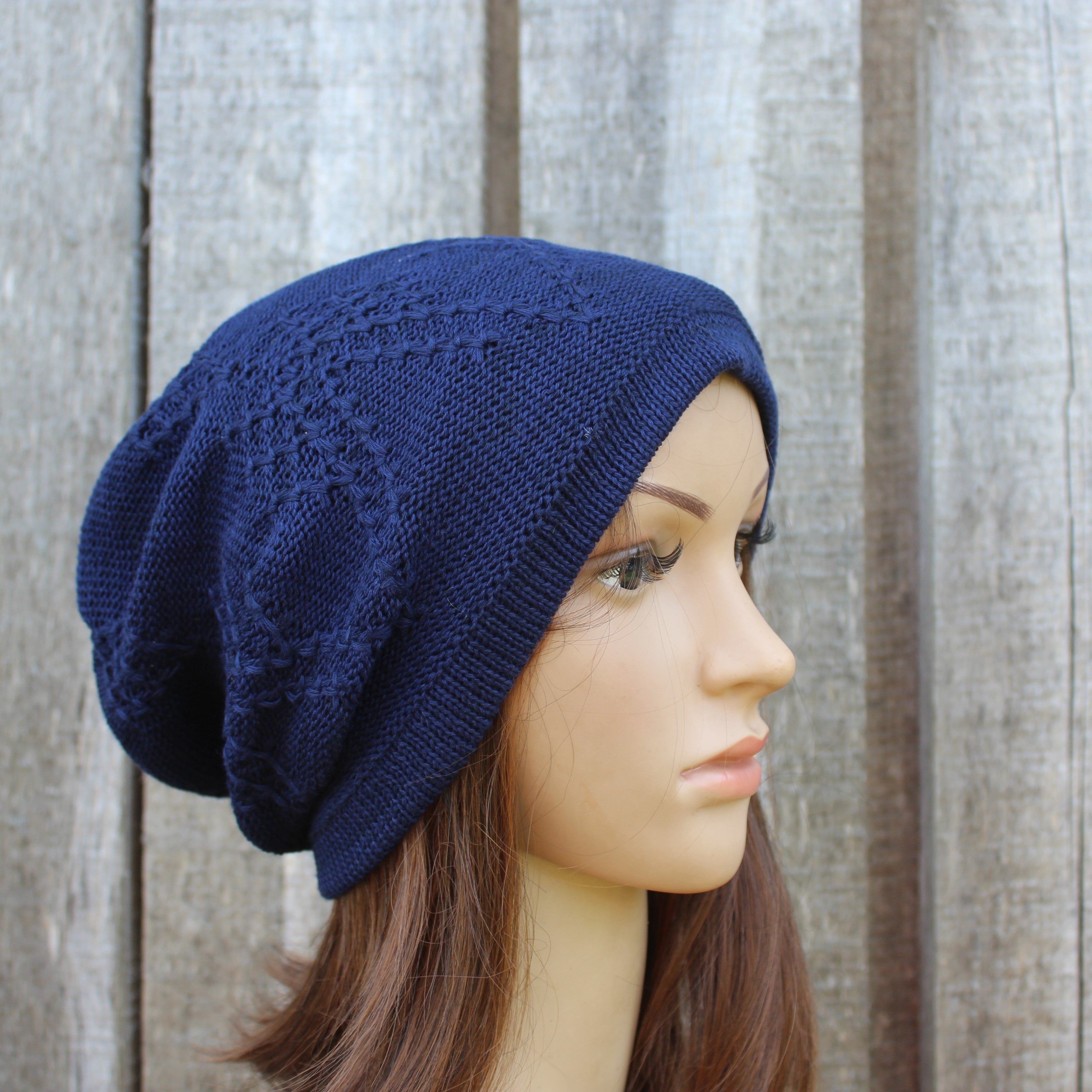 Navy blue knitted beanie on a mannequin head against a wooden background