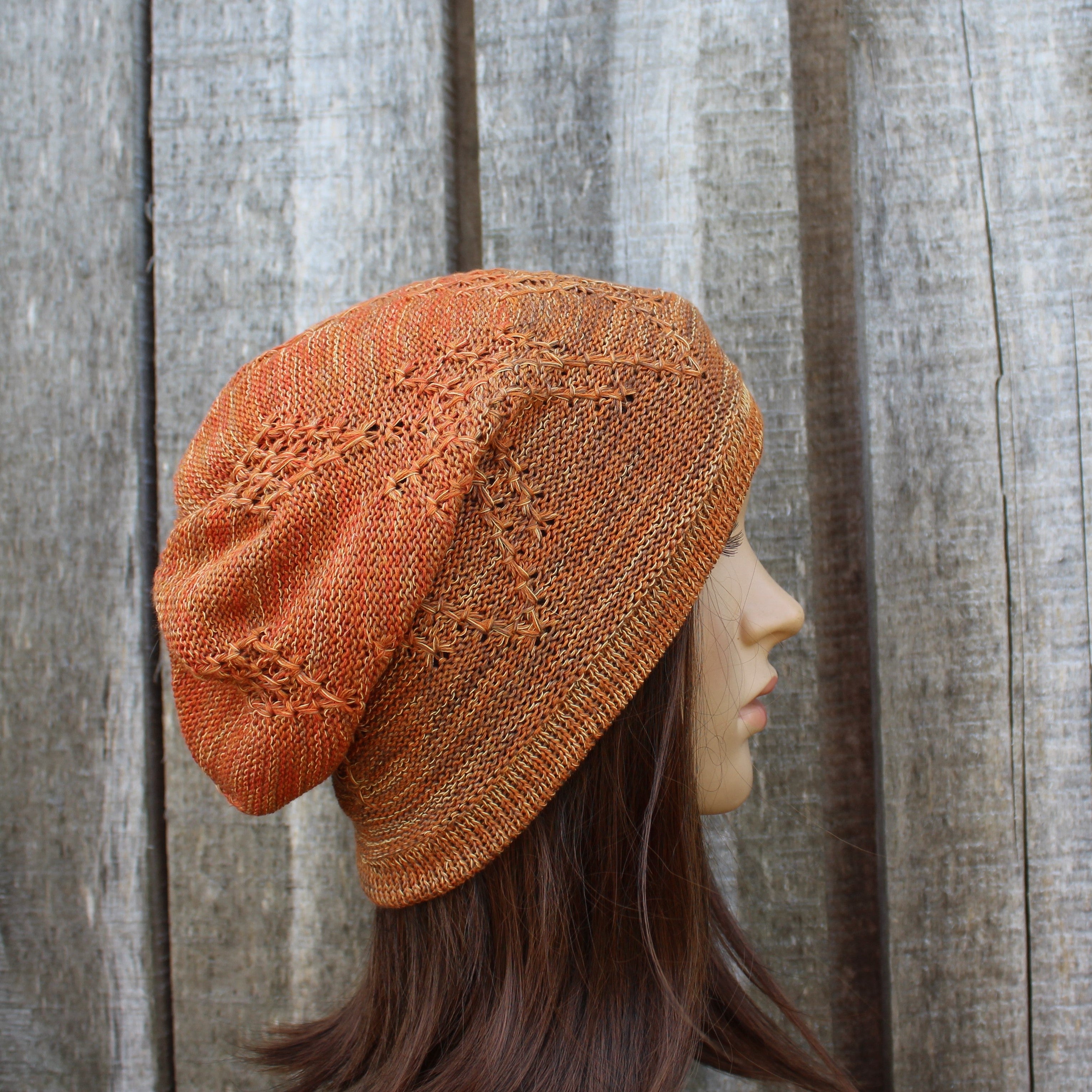 Knitted orange beanie on a mannequin head against a wooden background