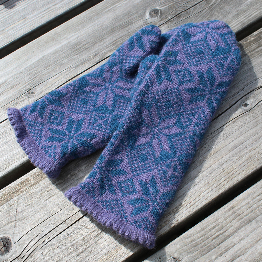 Pair of blue and purple patterned mittens on a wooden surface