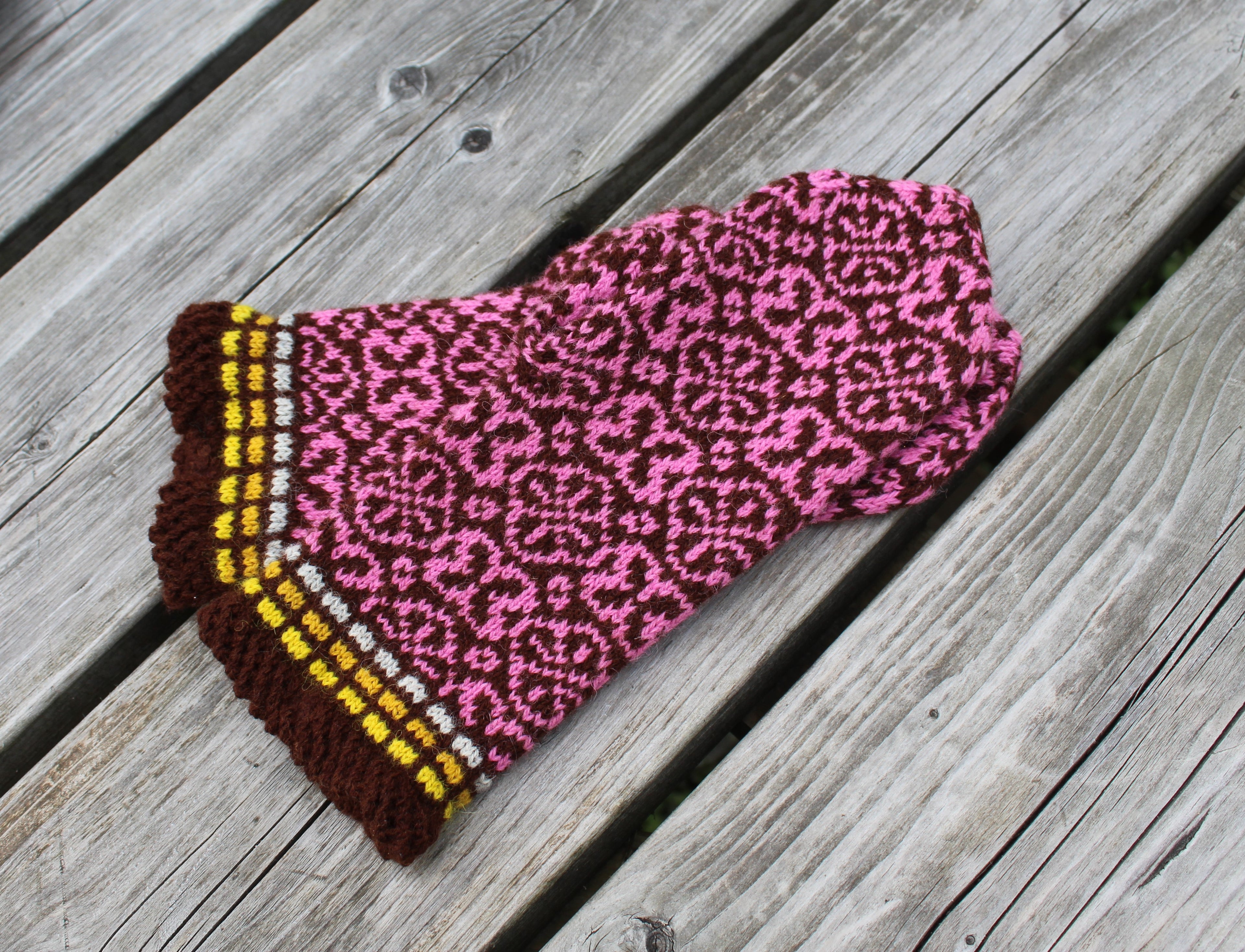 Knitted scarf with pink leopard print and brown border on wooden surface