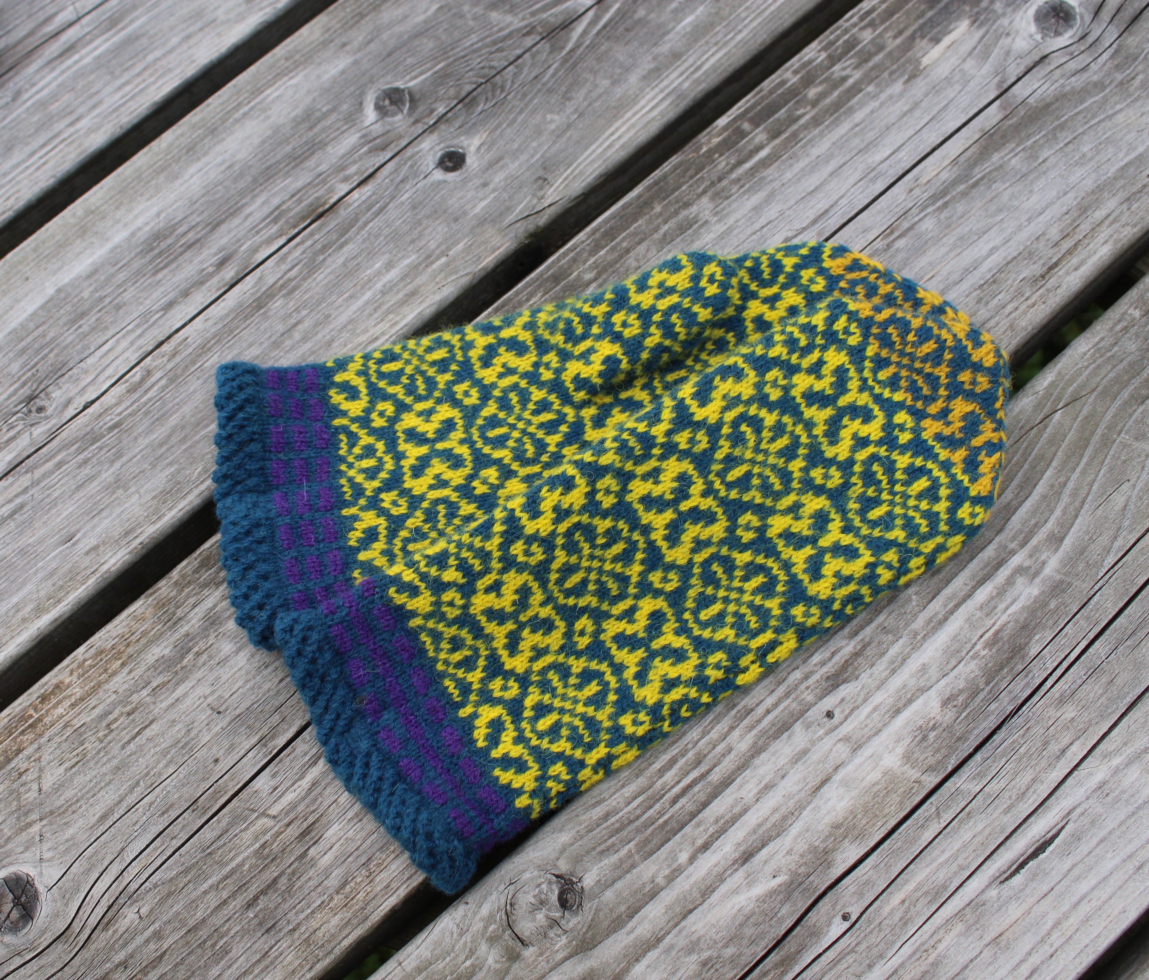 Knitted green and blue patterned hat on a wooden surface