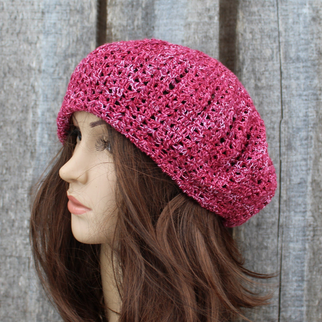 Pink knitted beret worn by a mannequin against a wooden background