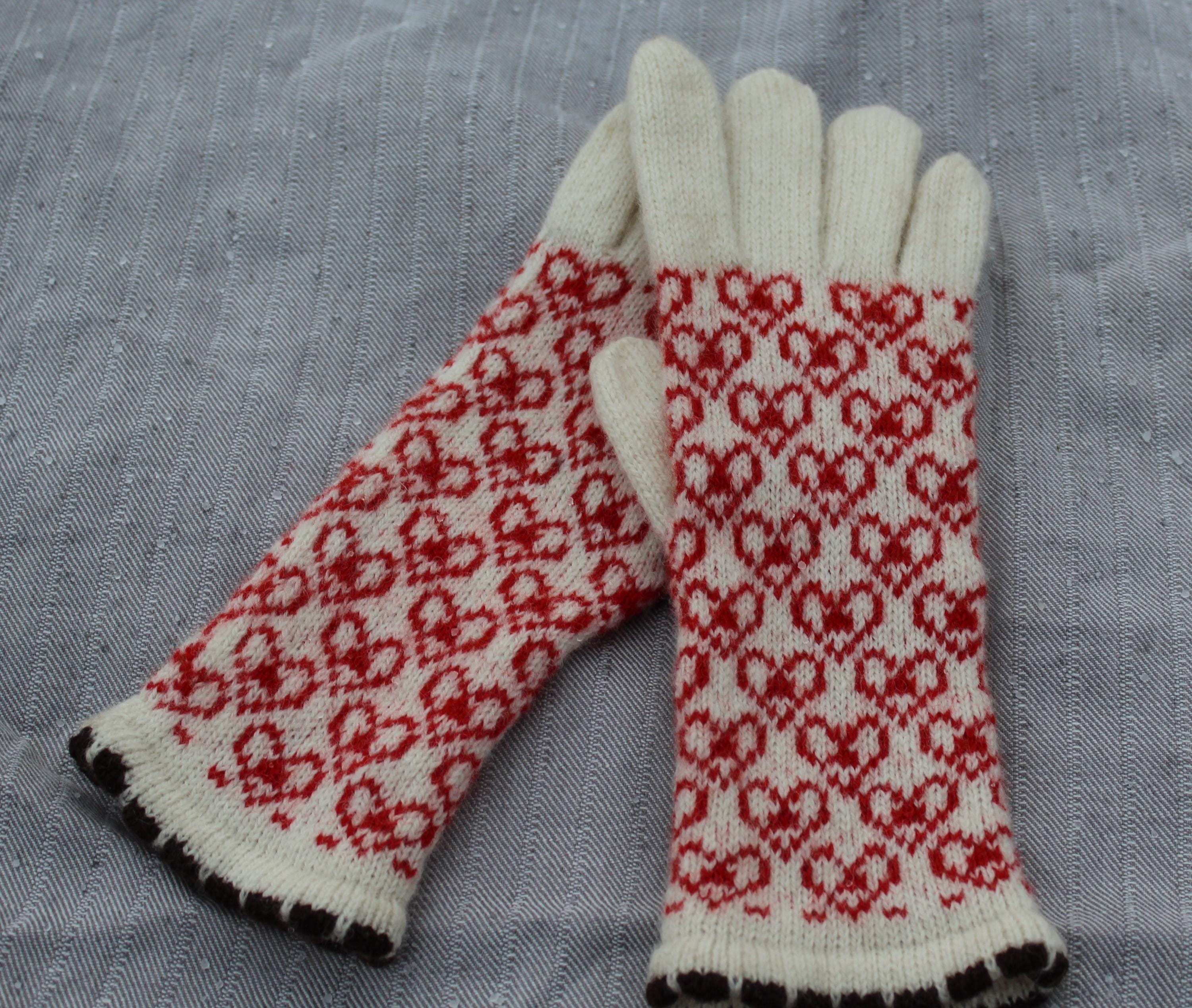 Pair of gloves with red and white pattern on a gray fabric background