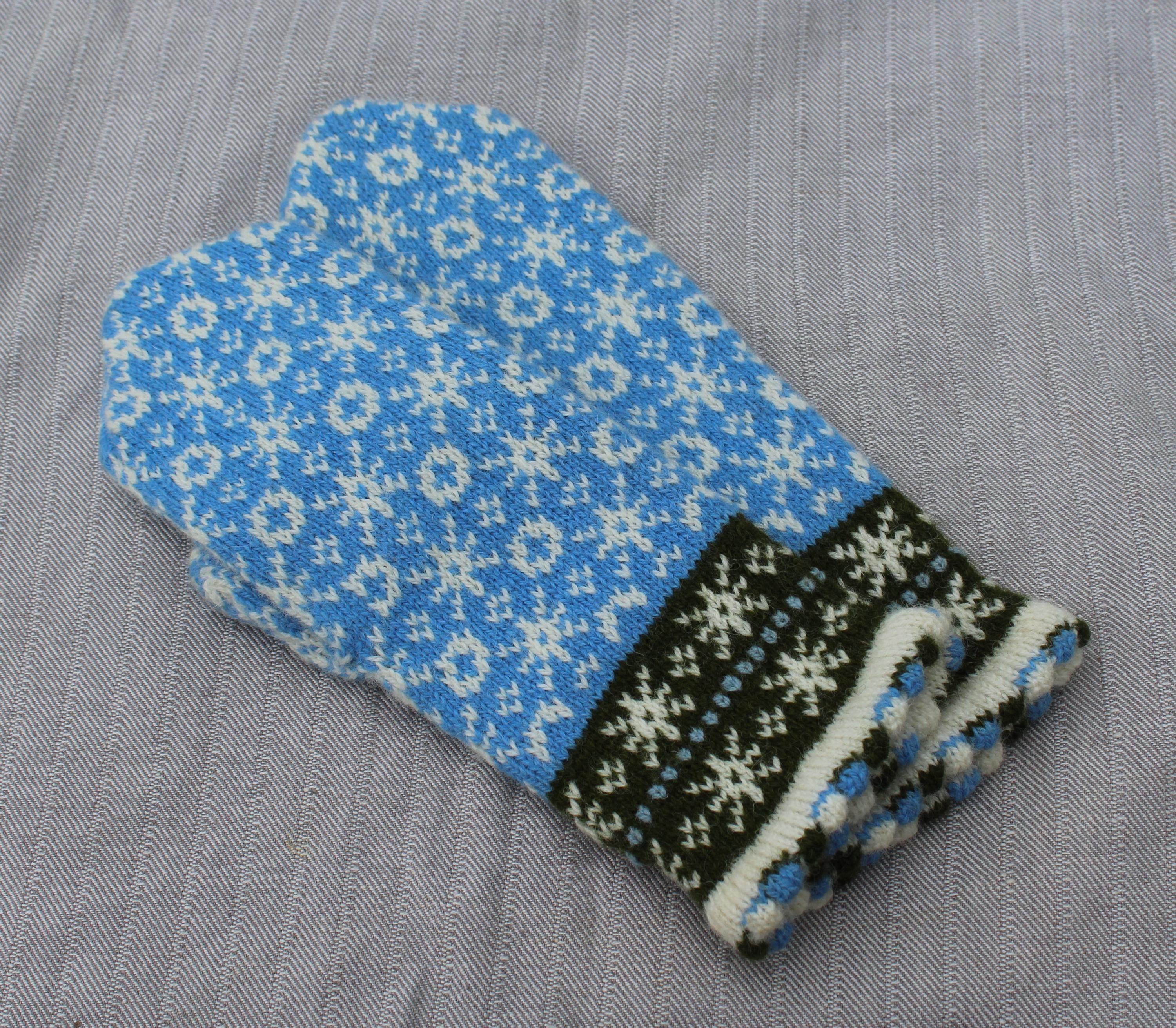 Knitted blue and black patterned glove on a gray background
