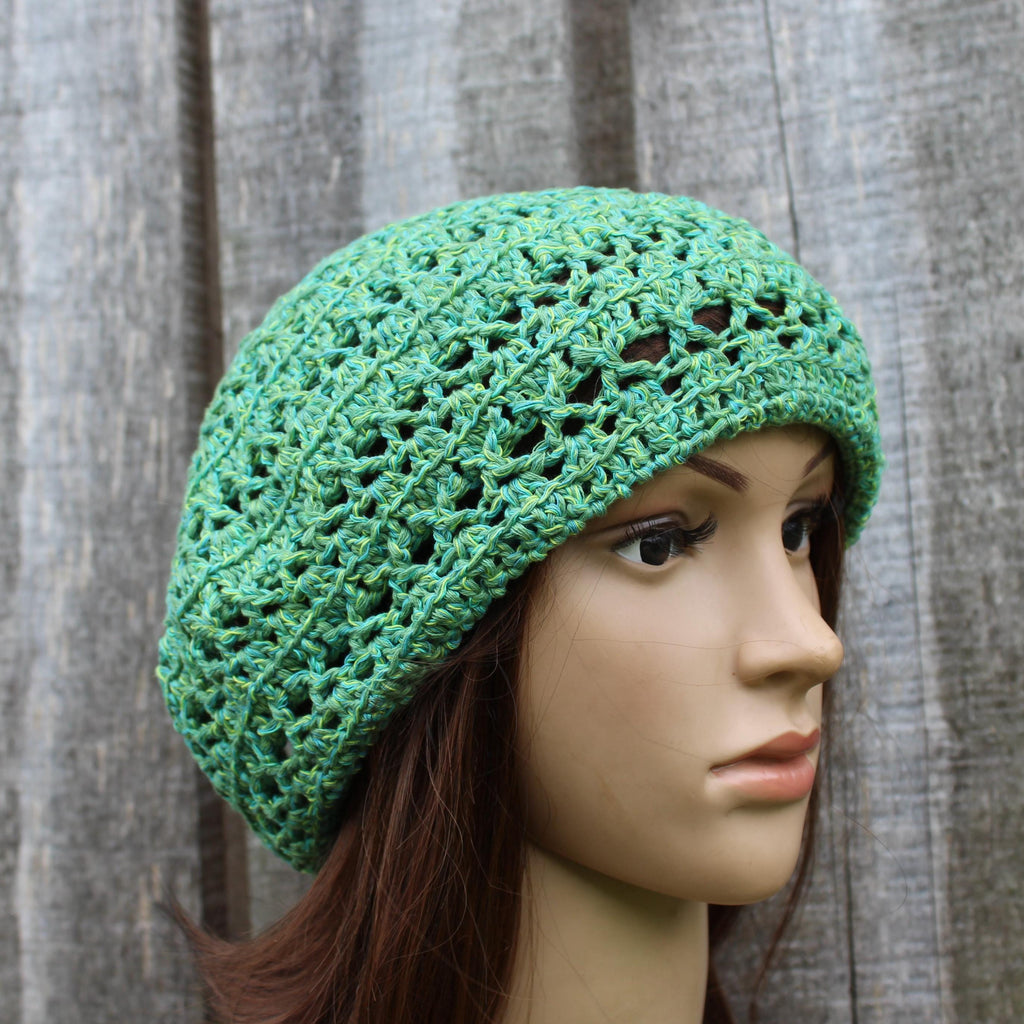 Green crochet hat on a mannequin head against a wooden background