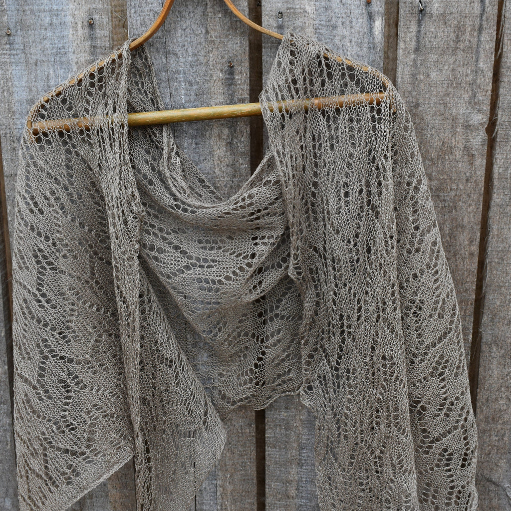 Knitted shawl on a wooden hanger against a rustic wooden background
