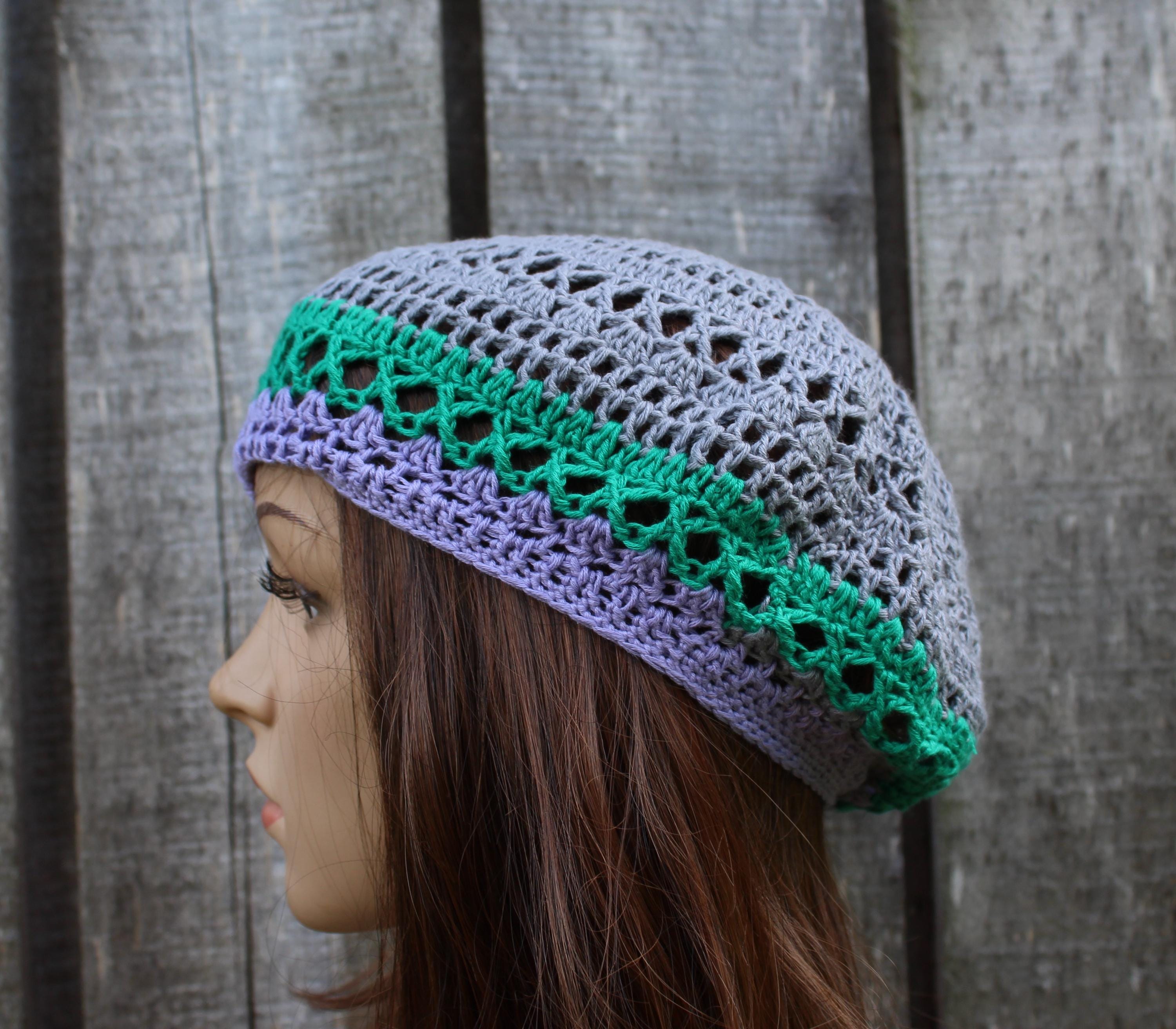 Crocheted hat with green and purple trim on a wooden background