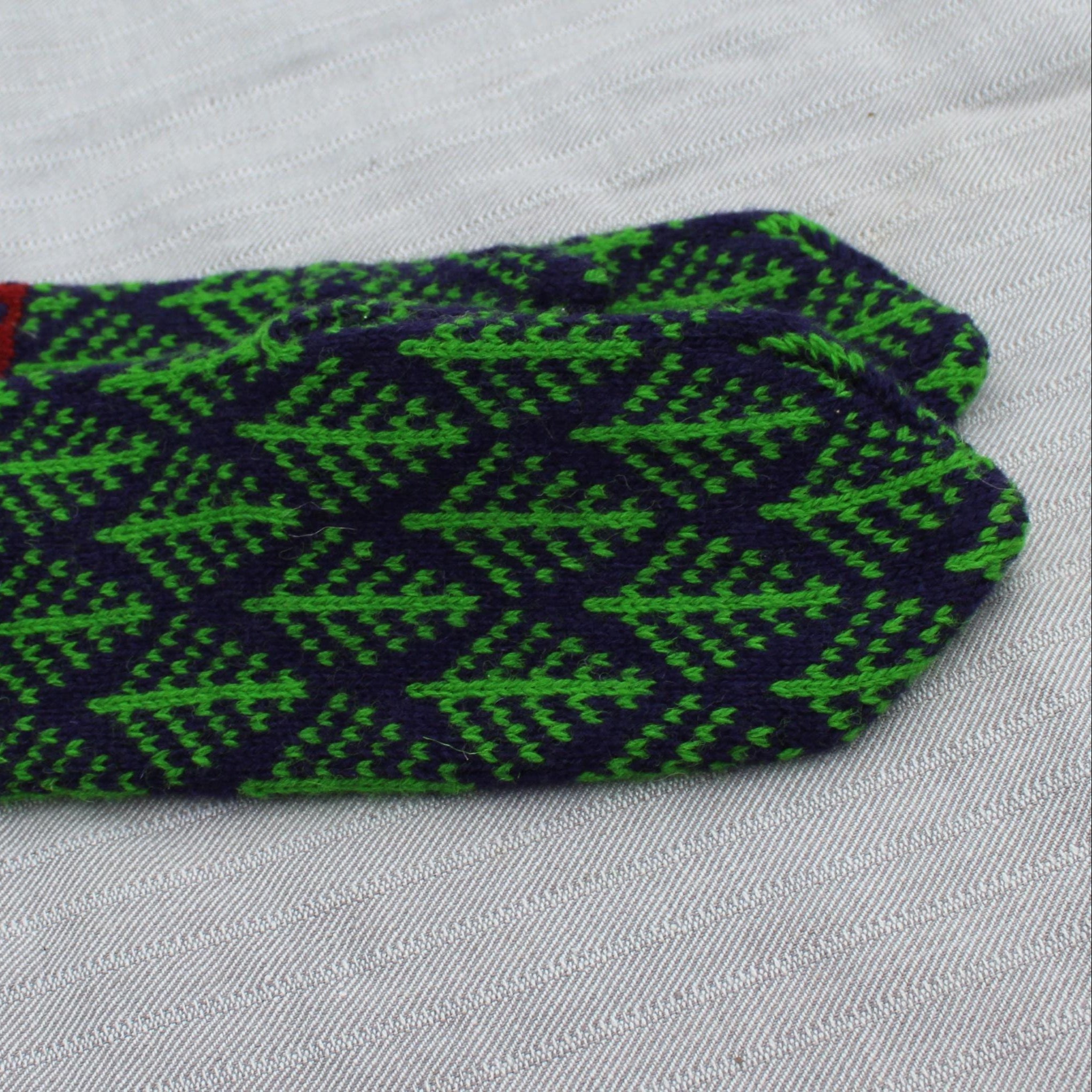 Pair of green and navy patterned mittens on a light gray background