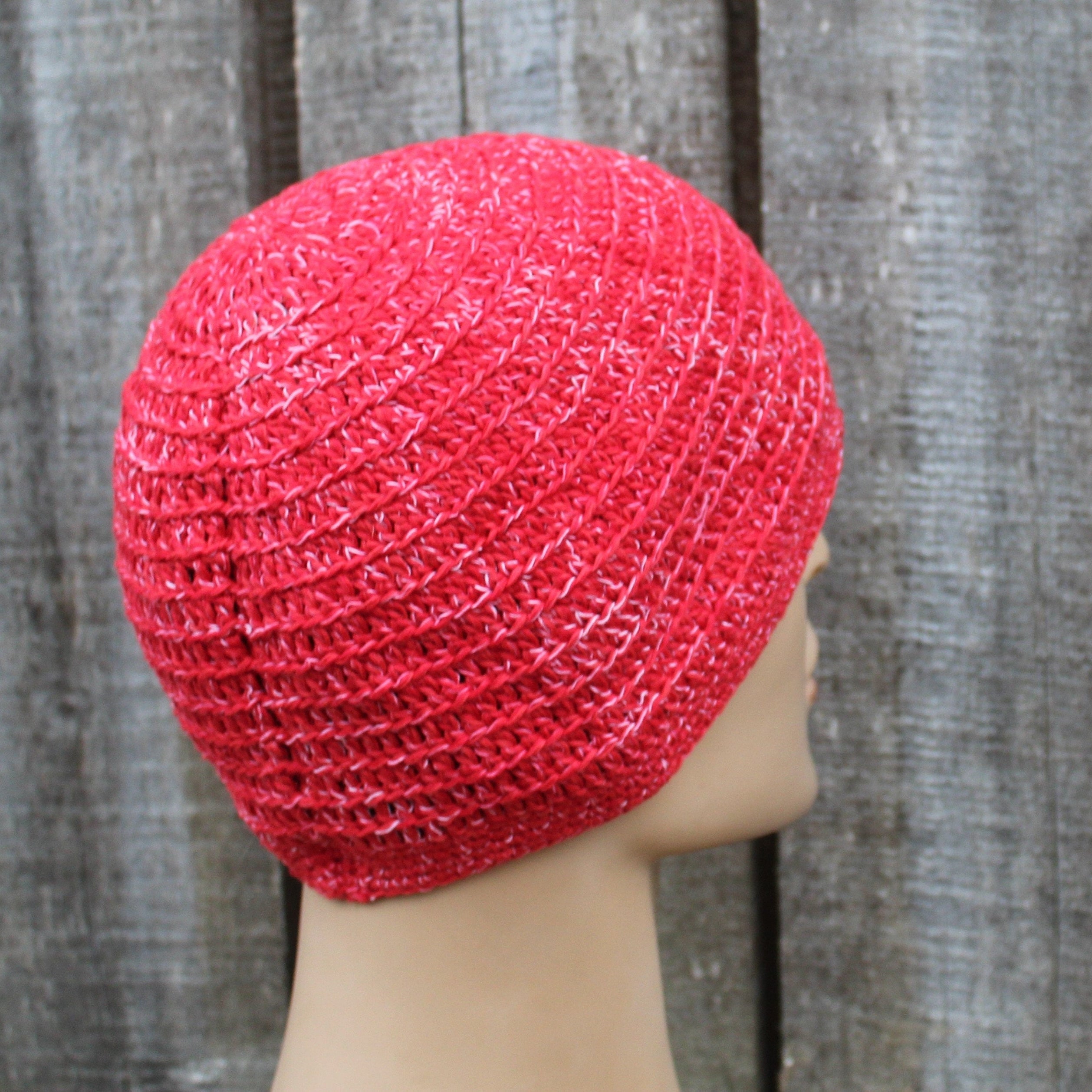 Red knitted hat on a mannequin head against a wooden background