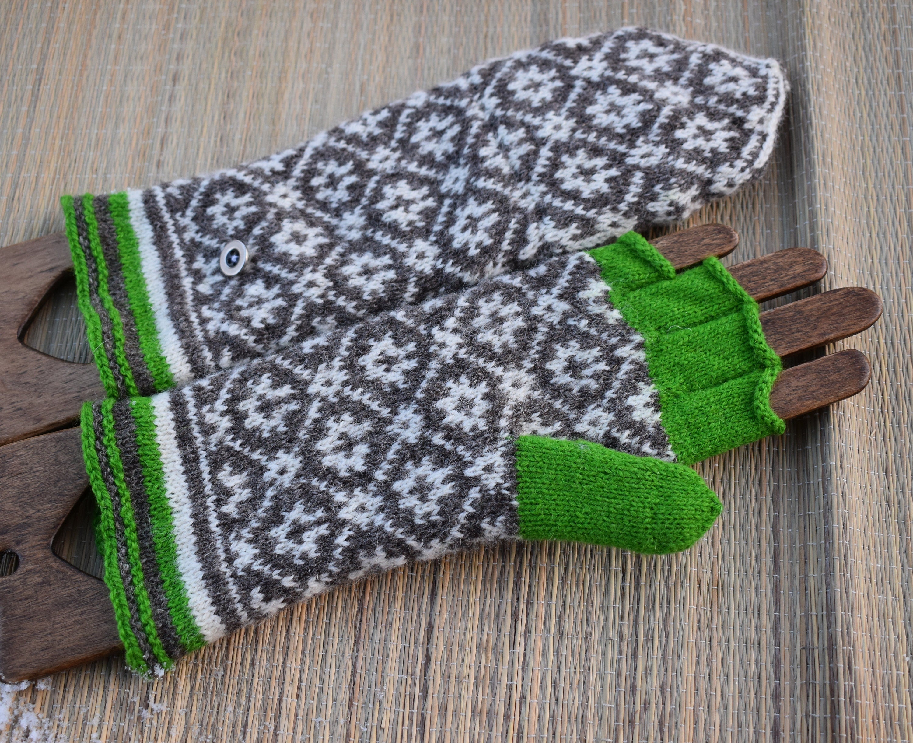Pair of patterned gloves with green cuffs and edges on a wooden surface